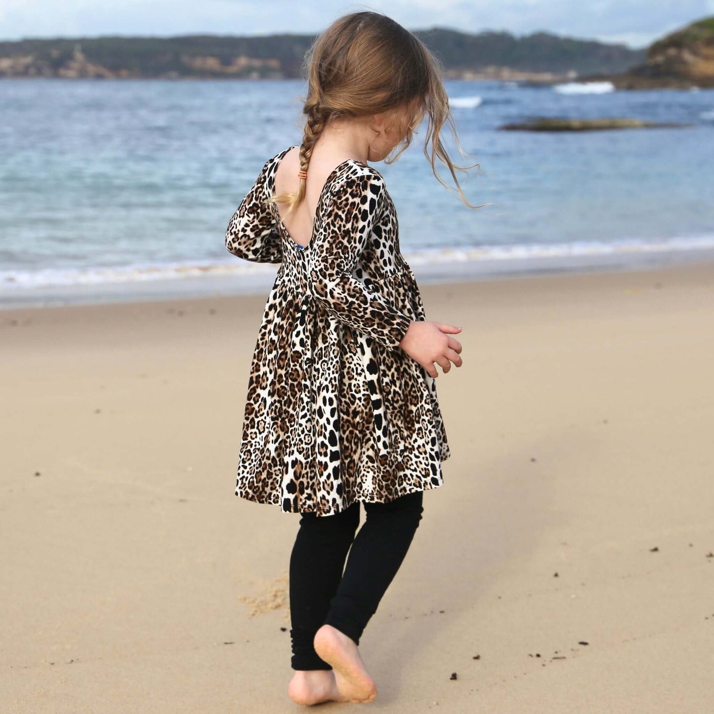 girl wearing animal printed long sleeve dress featuring low back and gathered waist skirt. Ethically made in australia with a stretch viscose jersey fabric.