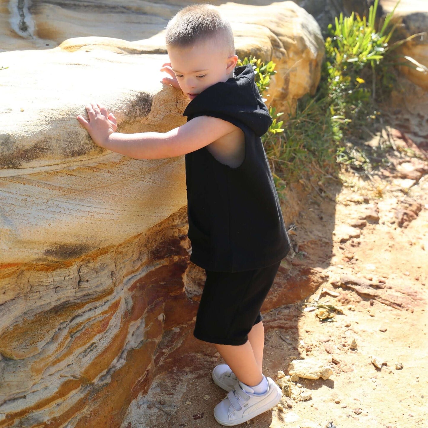 Boy wearing Black drop crotch shorts with white contrast drawcord and elastic waistband. Ethically made in Australia with a 100% cotton french terry fabric