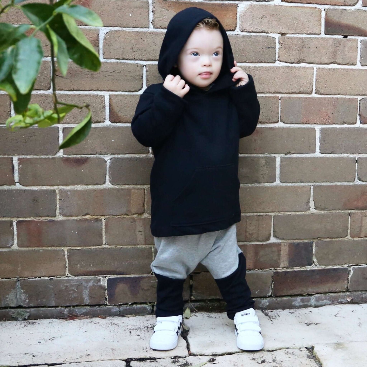 boy wearing black long sleeve hoodie featuring front pouch pocket. Ethically made in australia with 100% cotton french terry