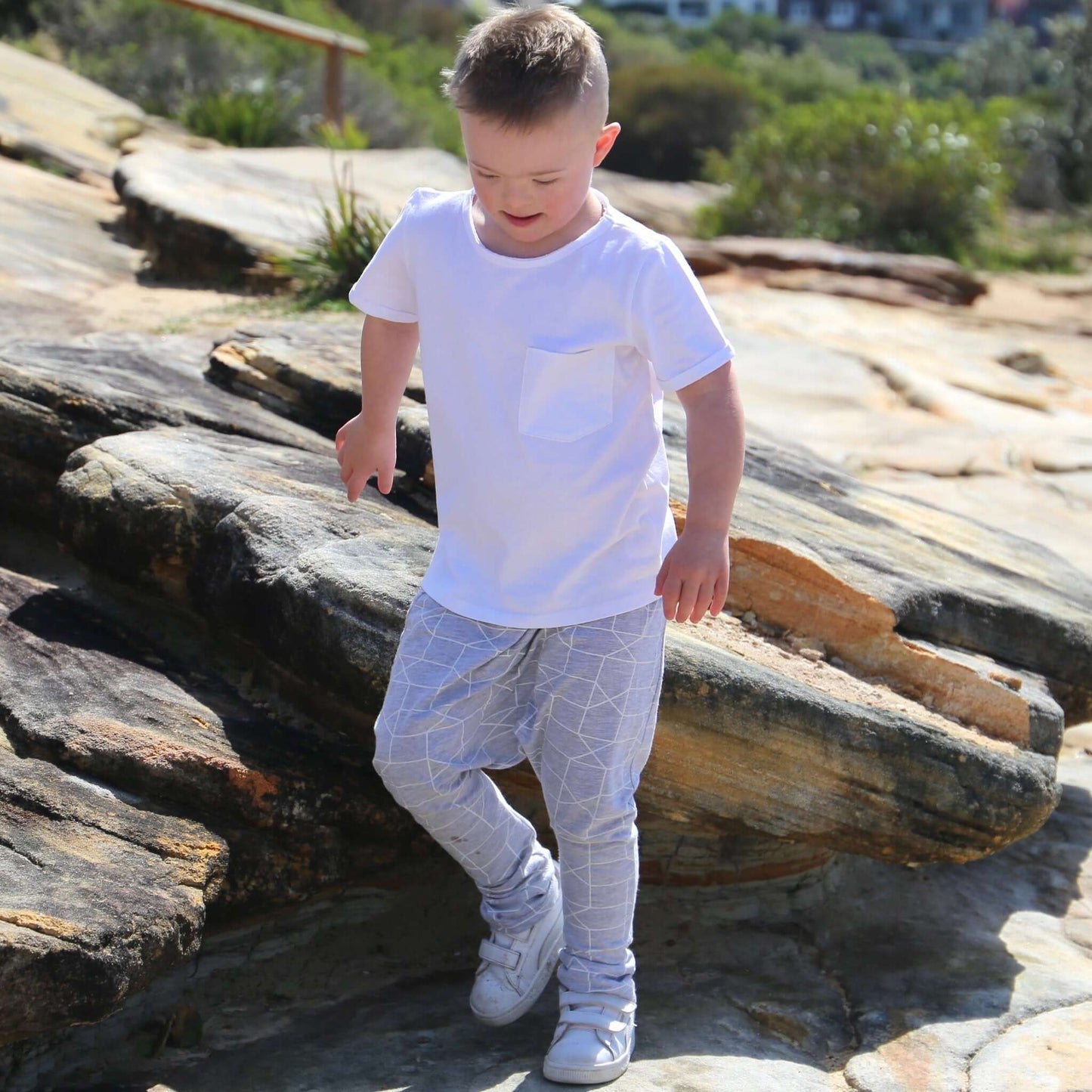 boy wearing grey marle/white printed harem pant featuring an elastic waistband. Ethically made in australia with a stretch cotton jersey