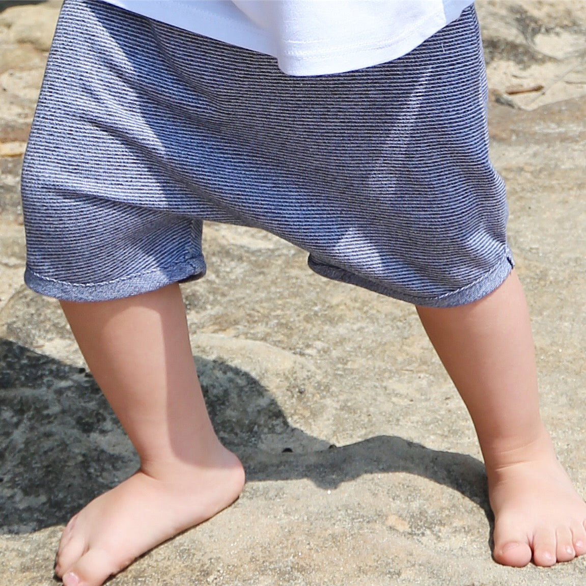 Boy wearing Blue stripe drop crotch shorts with white contrast drawcord and elastic waistband. Ethically made in Australia with a 100% cotton jersey