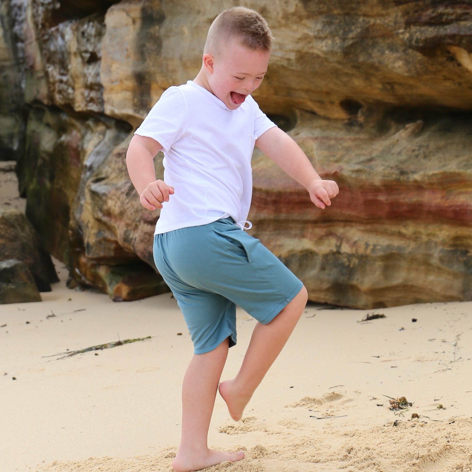 Boy wearing Ocean colour drop crotch shorts with contrast white drawcord and elastic waistband.  ethically made in australia with 100% cotton jersey.