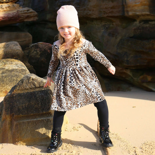 girl wearing animal printed long sleeve dress featuring low back and gathered waist skirt.  Ethically made in australia with a stretch viscose jersey fabric.