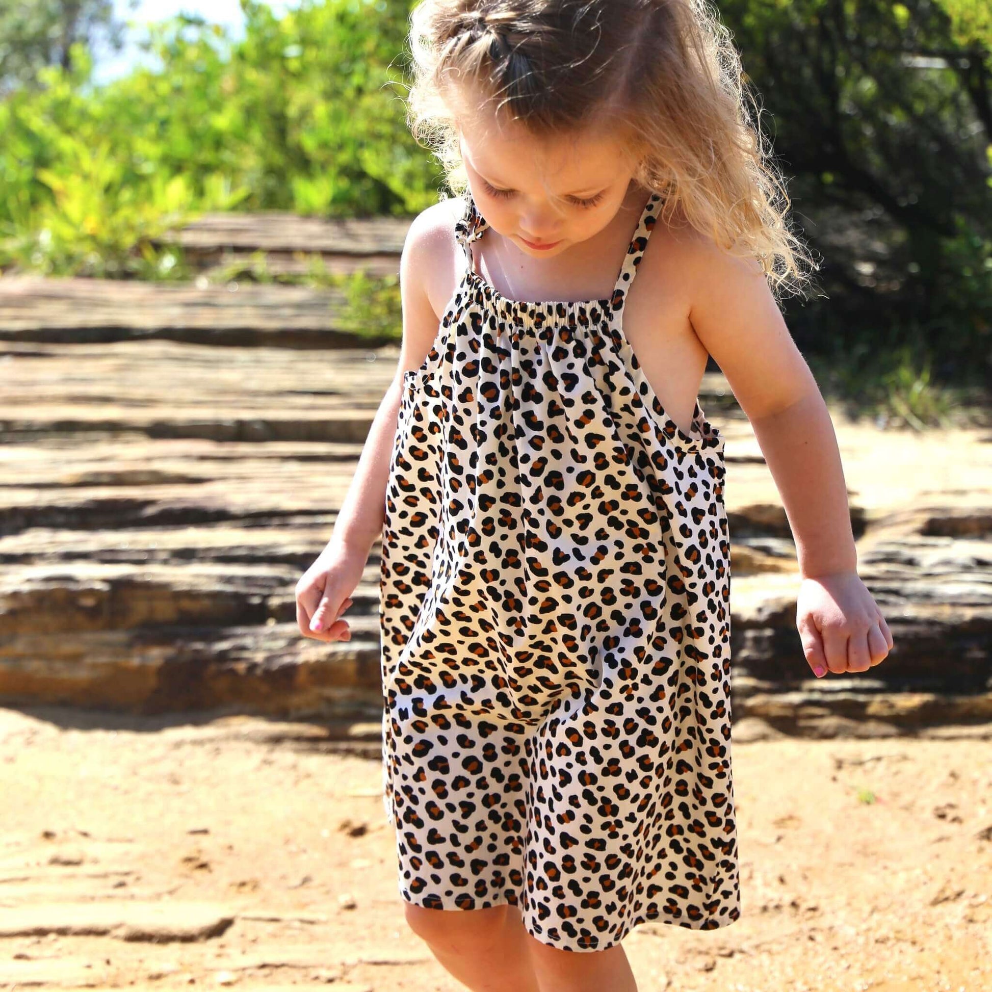 girl wearing animal printed cotton poplin a-line dress with shoulder strap ties.  Ethically made in australia with 100% printed cotton poplin