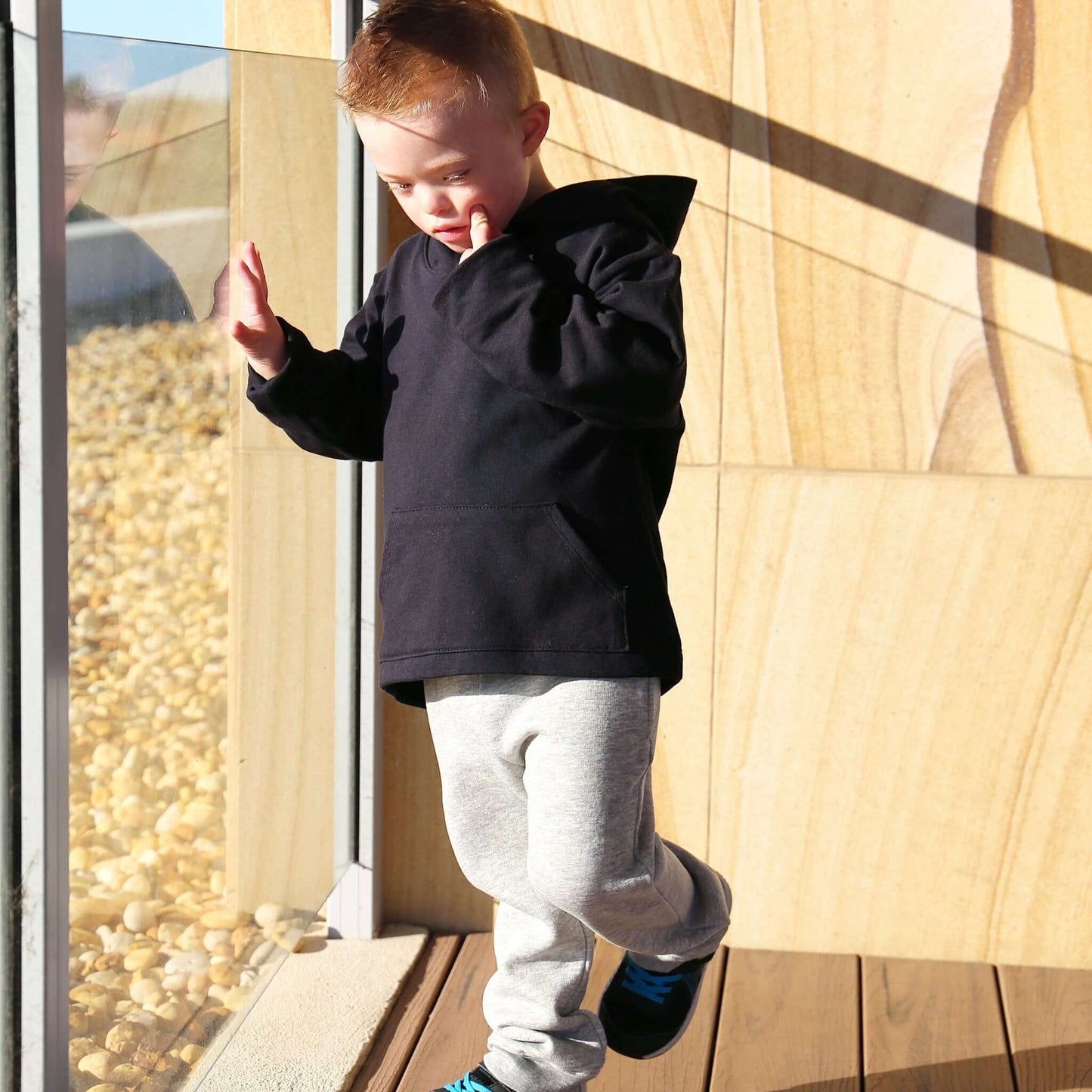 boy wearing black long sleeve hoodie featuring front pouch pocket. Ethically made in australia with 100% cotton french terry