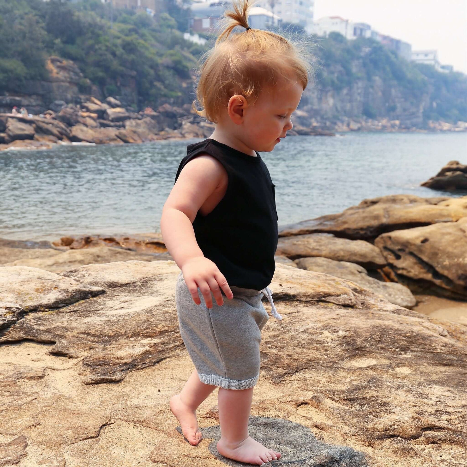 toddler girl wearing black singlet with front pocket. Ethically made in australia with 100% cotton jersey