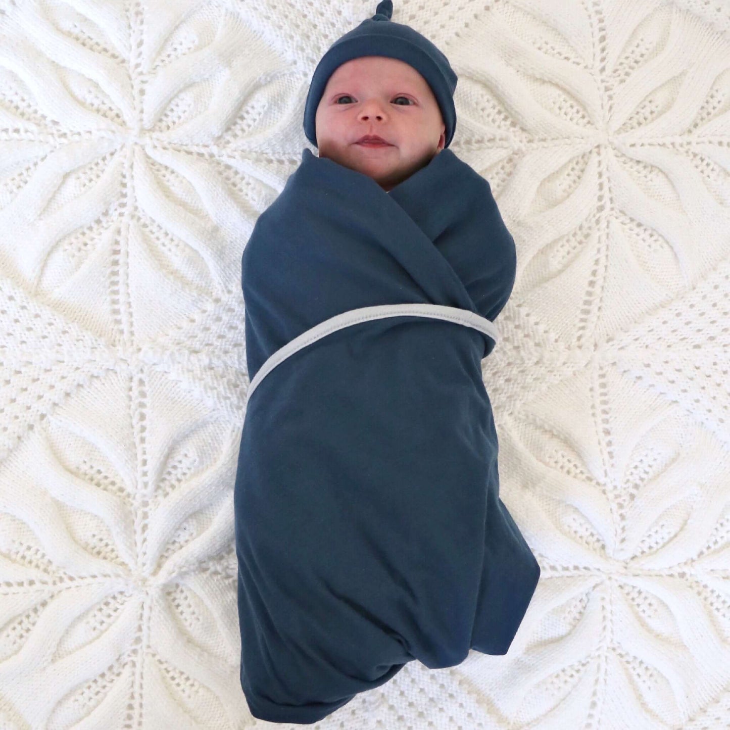 baby girl wrapped in blue colour swaddle. Ethically made in australia with 100% cotton jersey