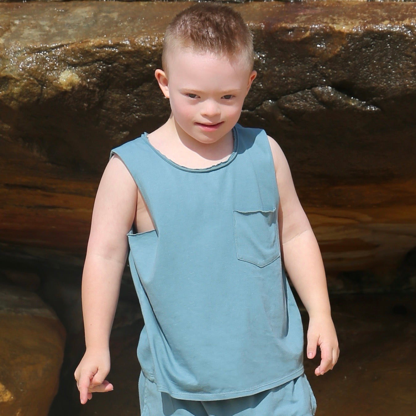 boy wearing ocean colour singlet with front pocket, raw edge armhole and neckline. Ethically made in australia with 100% cotton jerseye in australia with 100% cotton jersey