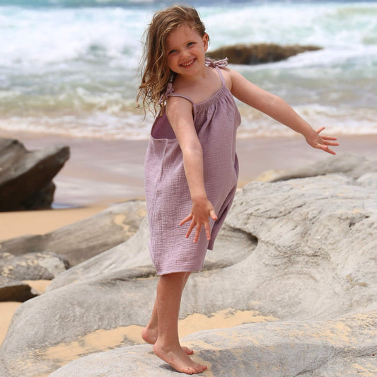 girl wearing an a-line dress with shoulder strap ties.  Ethically made in australia with 100% cotton cheesecloth