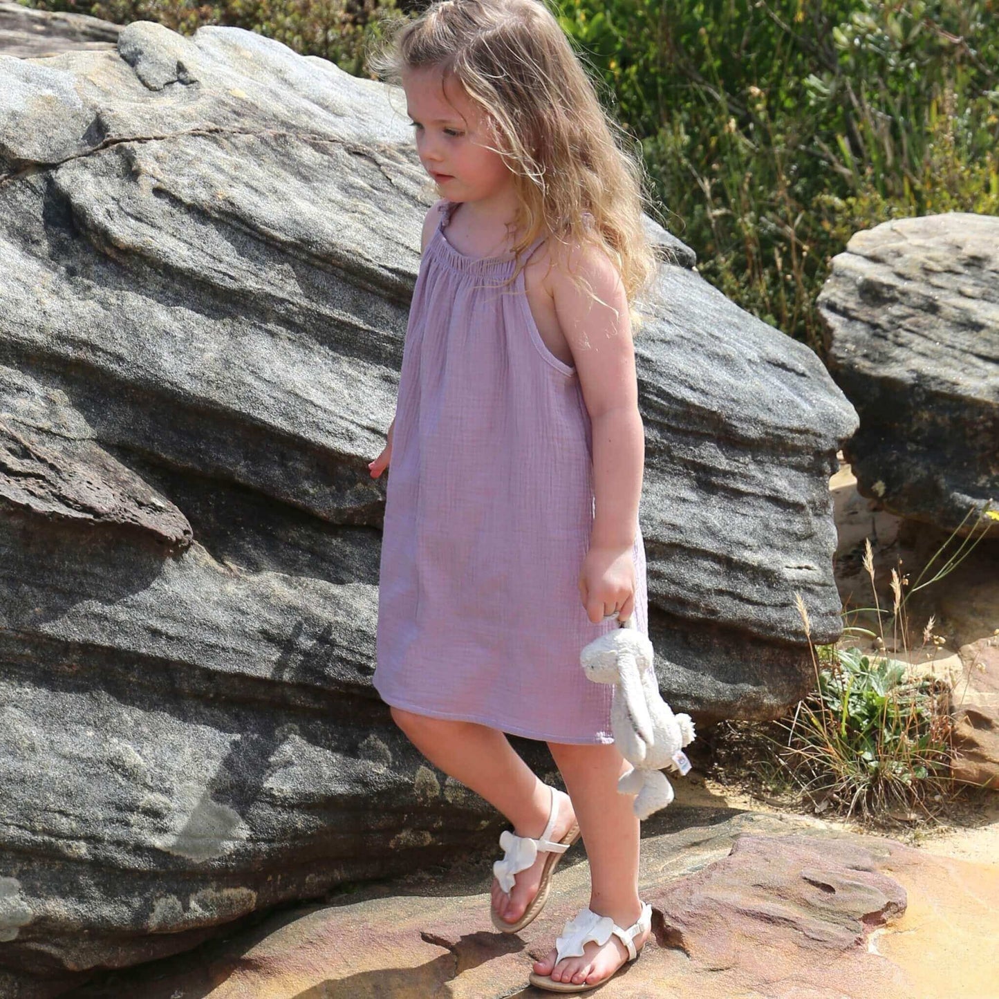 girl wearing an a-line dress with shoulder strap ties.  Ethically made in australia with 100% cotton cheesecloth