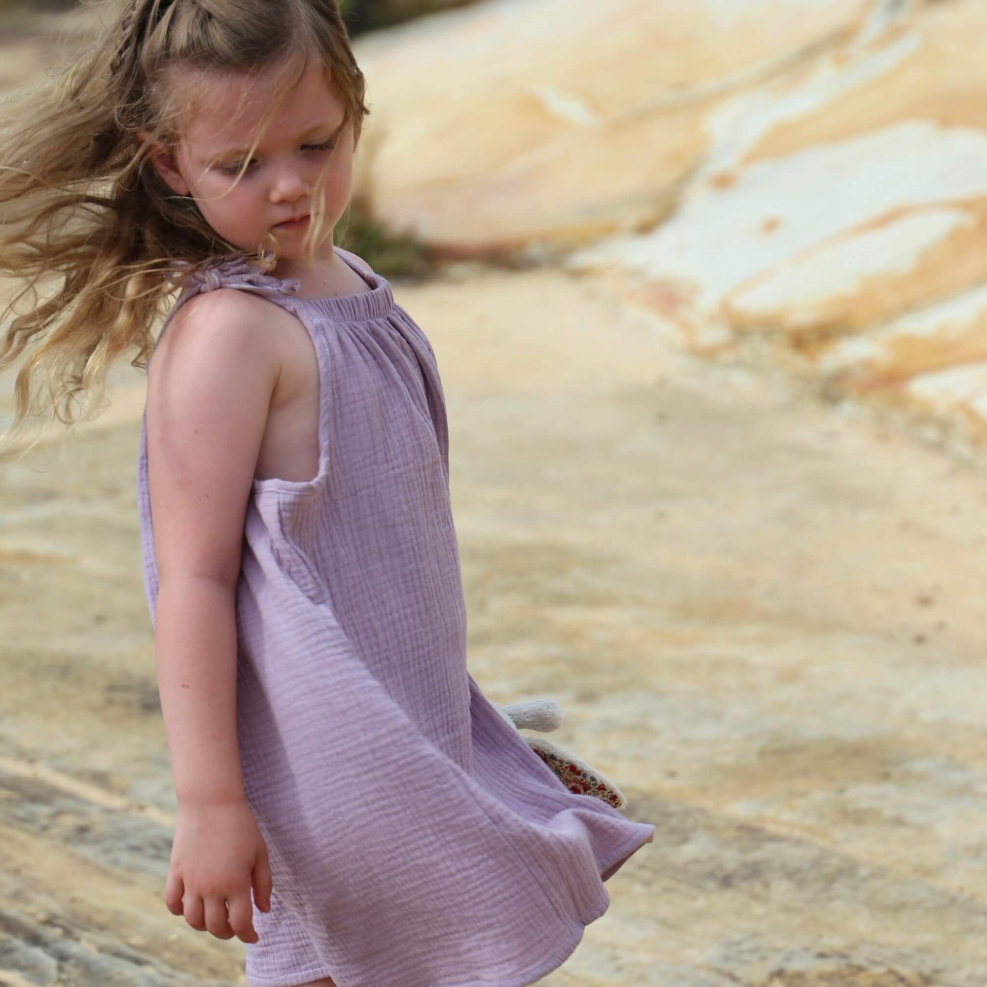 girl wearing an a-line dress with shoulder strap ties.  Ethically made in australia with 100% cotton cheesecloth