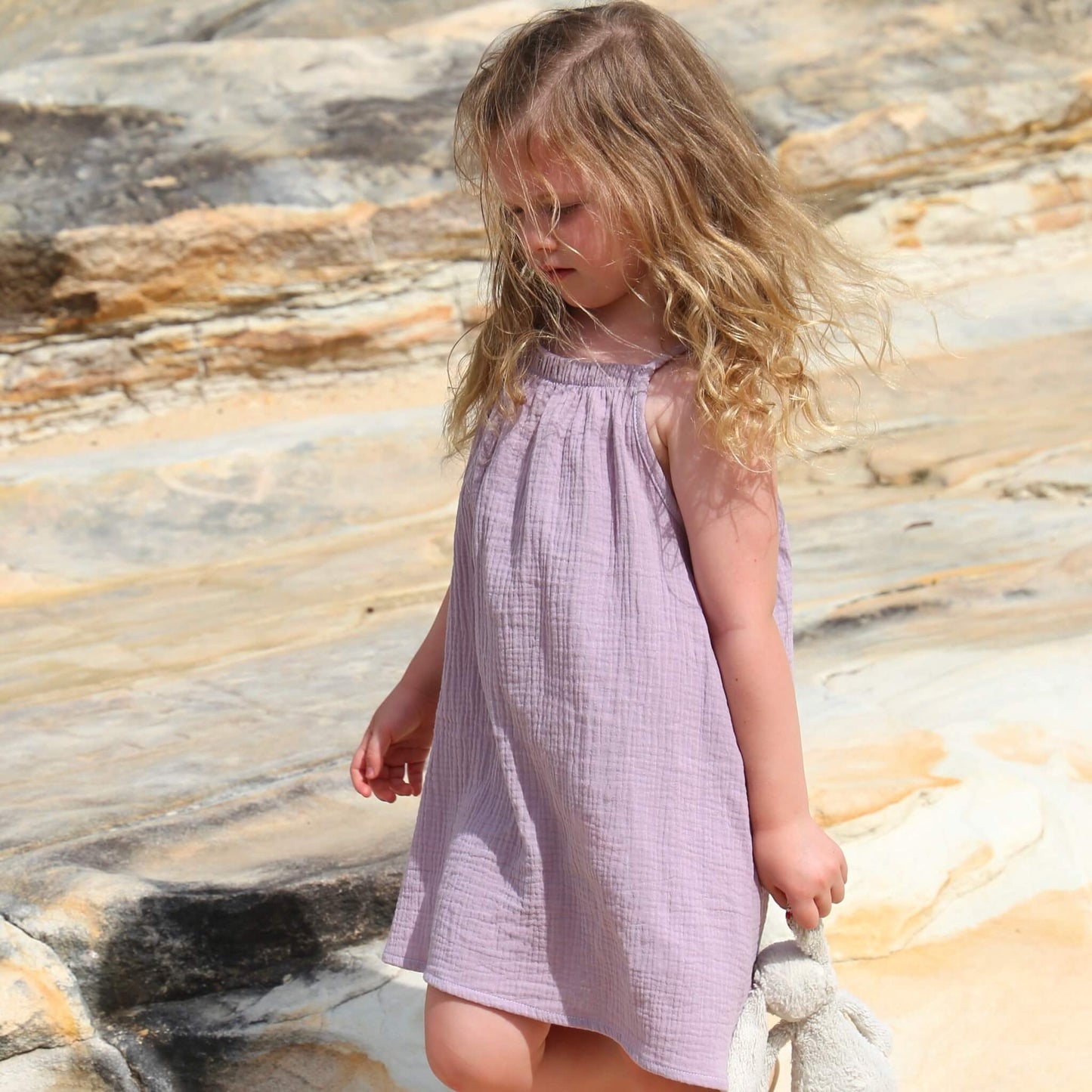 girl wearing an a-line dress with shoulder strap ties.  Ethically made in australia with 100% cotton cheesecloth