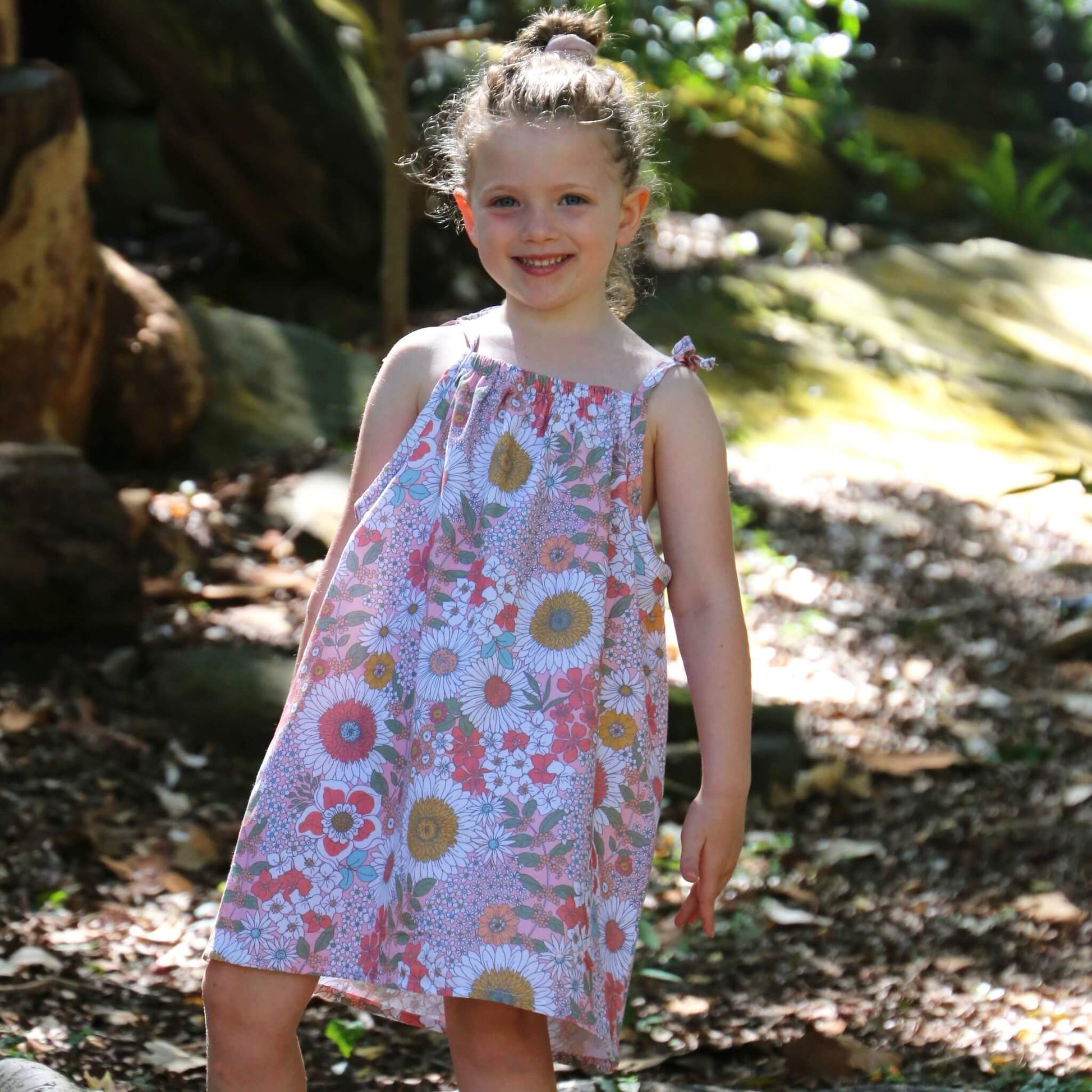 girl wearing Daisy printed cotton poplin a-line dress with shoulder strap ties.  Ethically made in australia with 100% printed cotton poplin