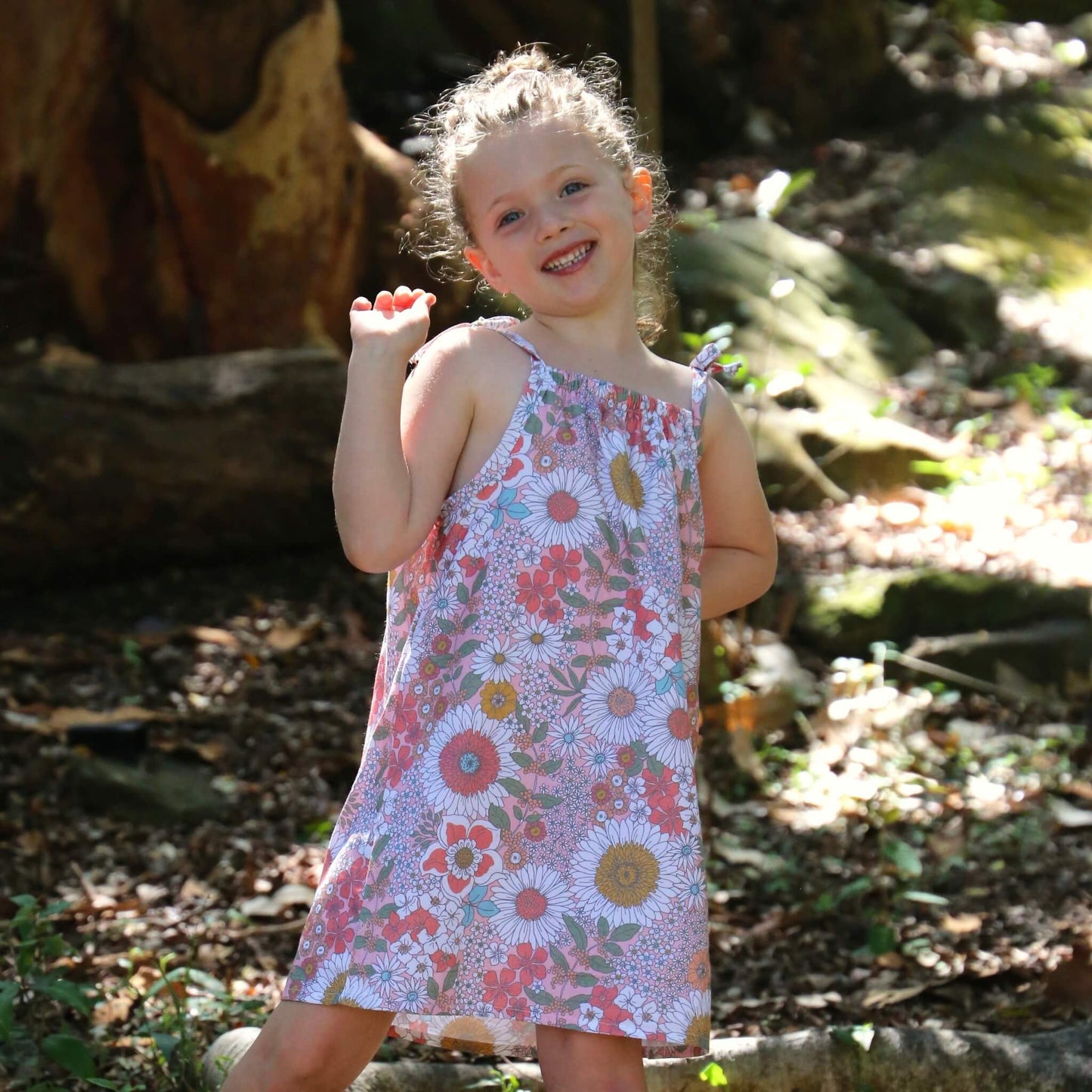 girl wearing Daisy printed cotton poplin a-line dress with shoulder strap ties.  Ethically made in australia with 100% printed cotton poplin