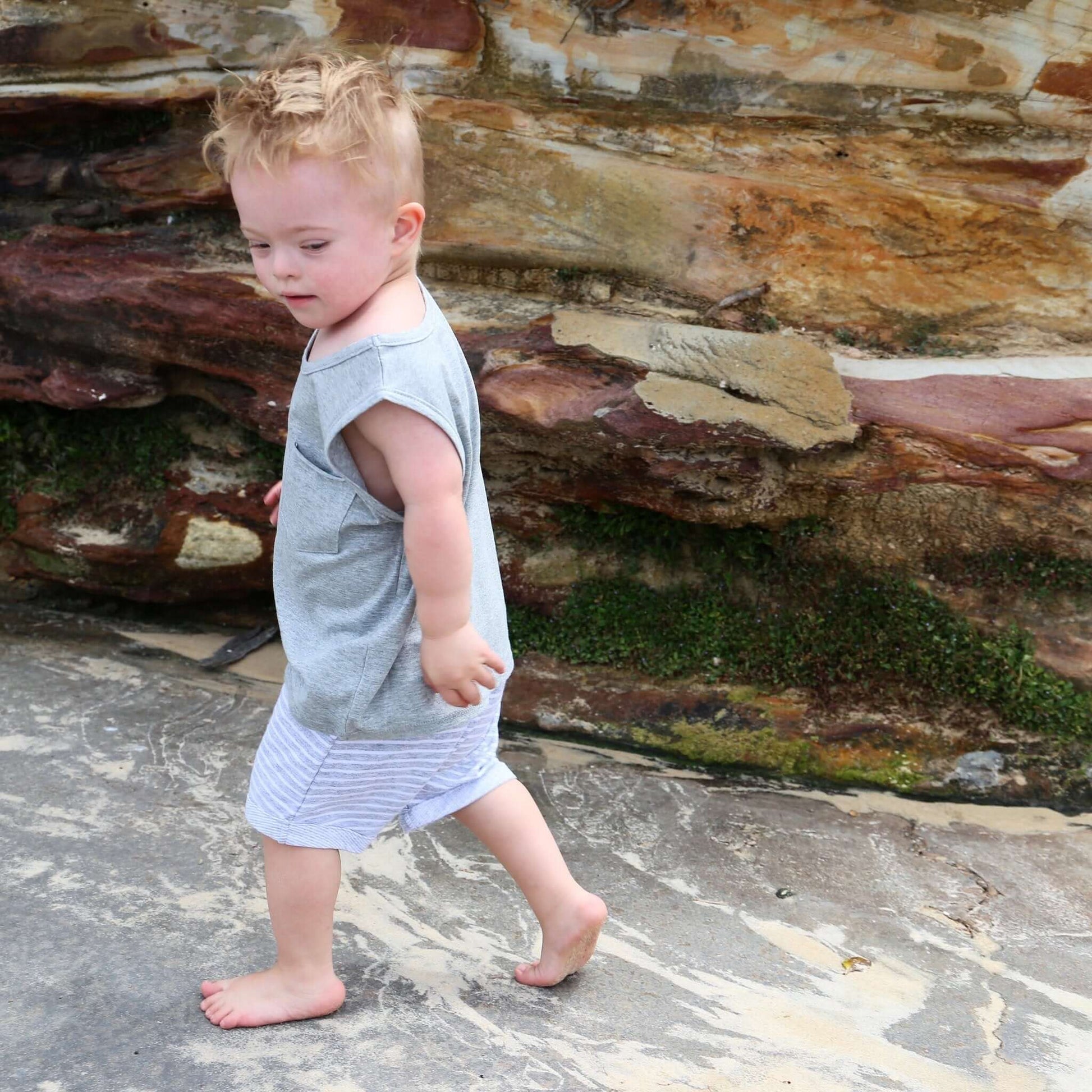 Toddler wearing grey jersey drop crotch shorts with white contrast stripe.  Ethically made in Australia with a soft stretch jersey fabric