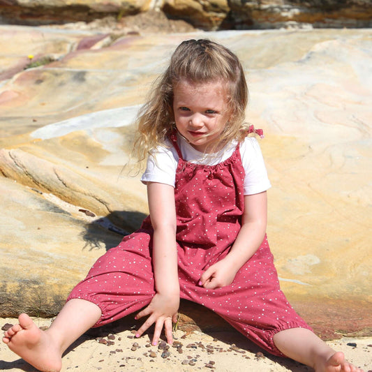 girl wearing rouge/white spot printed romper featuring tie straps and elastic leg cuff. ethically made in australia with 100% cotton drill.