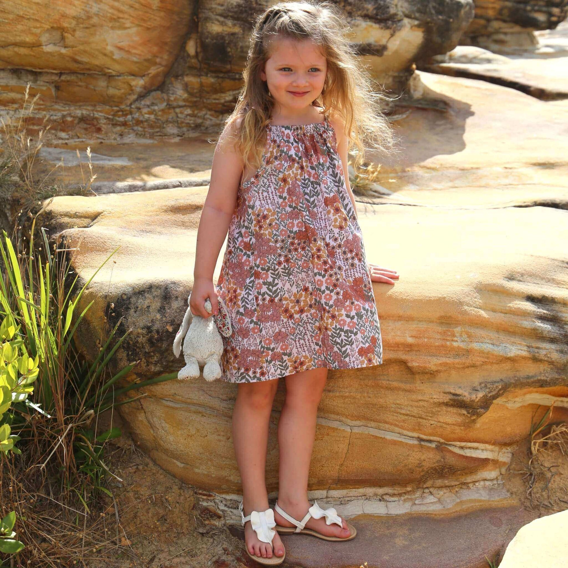 girl wearing floral printed cotton poplin a-line dress with shoulder strap ties.  Ethically made in australia with 100% printed cotton poplin