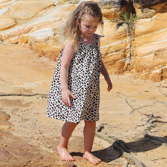 girl wearing animal printed cotton poplin a-line dress with shoulder strap ties.  Ethically made in australia with 100% printed cotton poplin