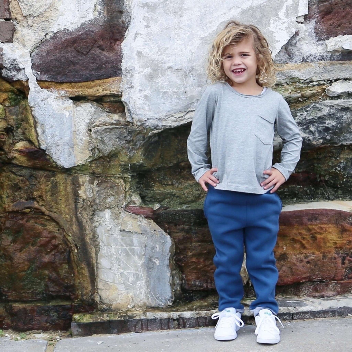 boy wearing grey marle long sleeve tshirt featuring front pocket and raw edge neckline. Ethically made in australia with 100% cotton jersey