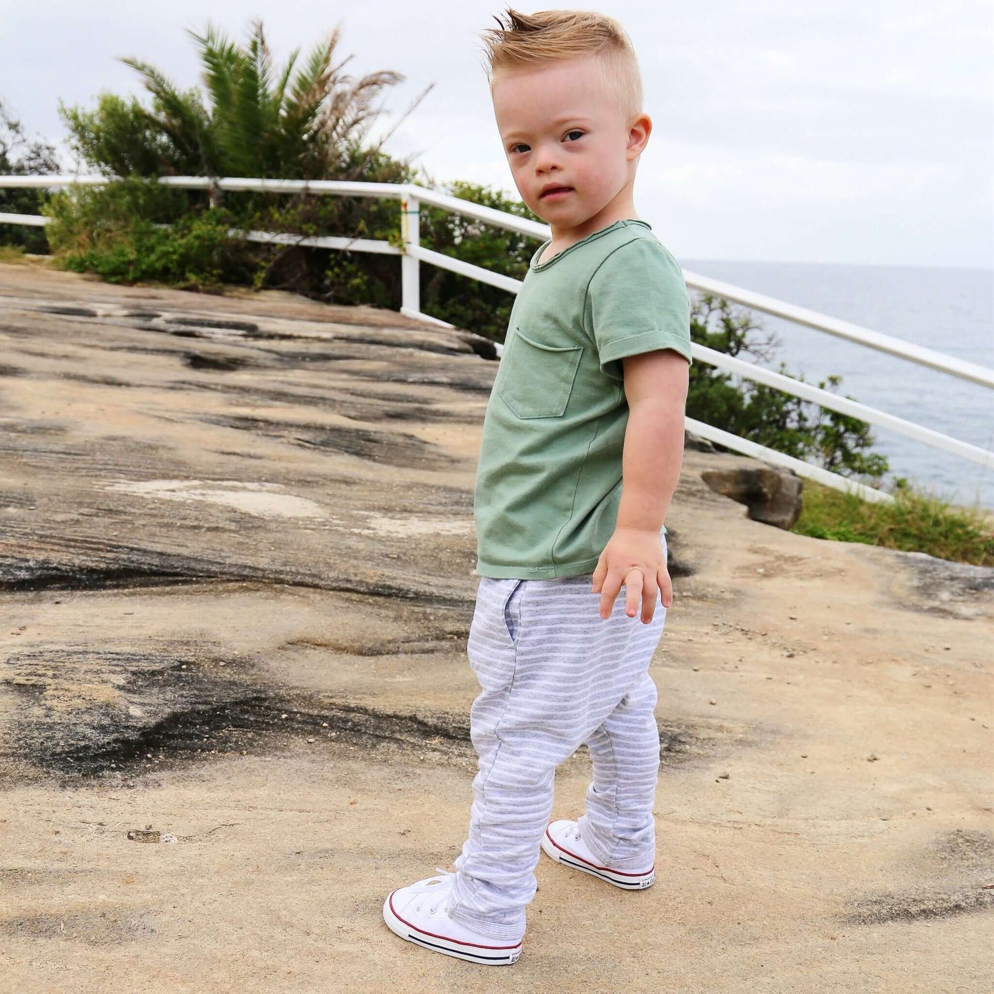 boy wearing grey marle with white stripe harem pant featuring an elastic waistband. Ethically made in australia with a stretch cotton jersey