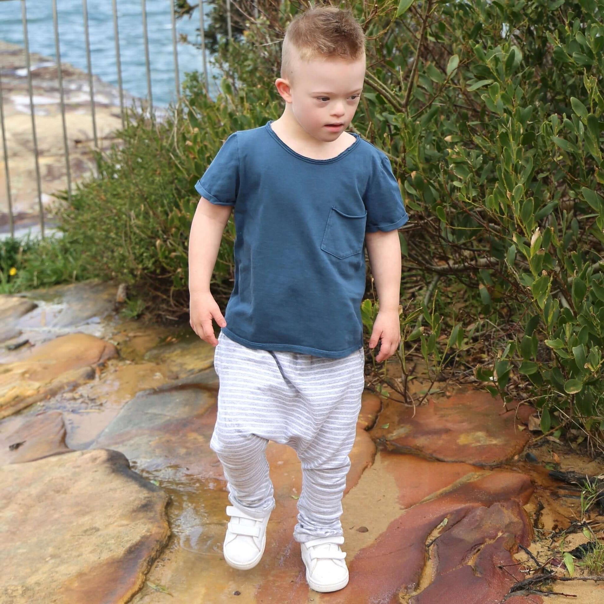 boy wearing grey marle with white stripe harem pant featuring an elastic waistband. Ethically made in australia with a stretch cotton jersey