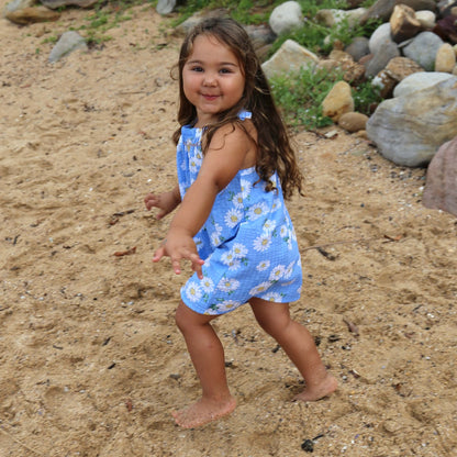 girl wearing blue colour daisy printed summer dress with adjustable tie straps.  Dress made with 100% Cotton printed seersucker