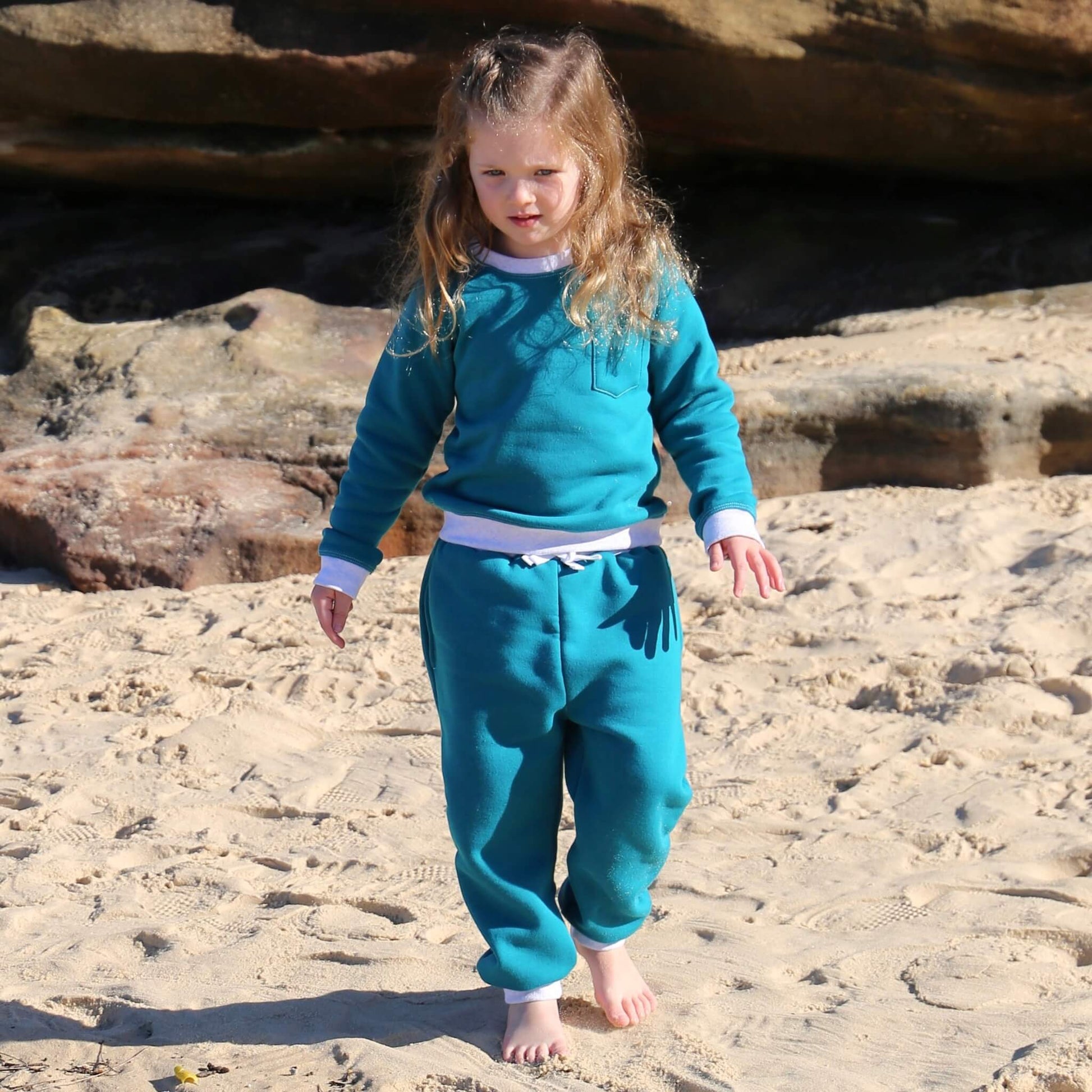 Girl wearing Jade coloured Winter Sweater featuring White Marle contrast rib at neck, hem and cuff with front pocket ethically made in Australia with Cotton blend cosy and warm Fleece