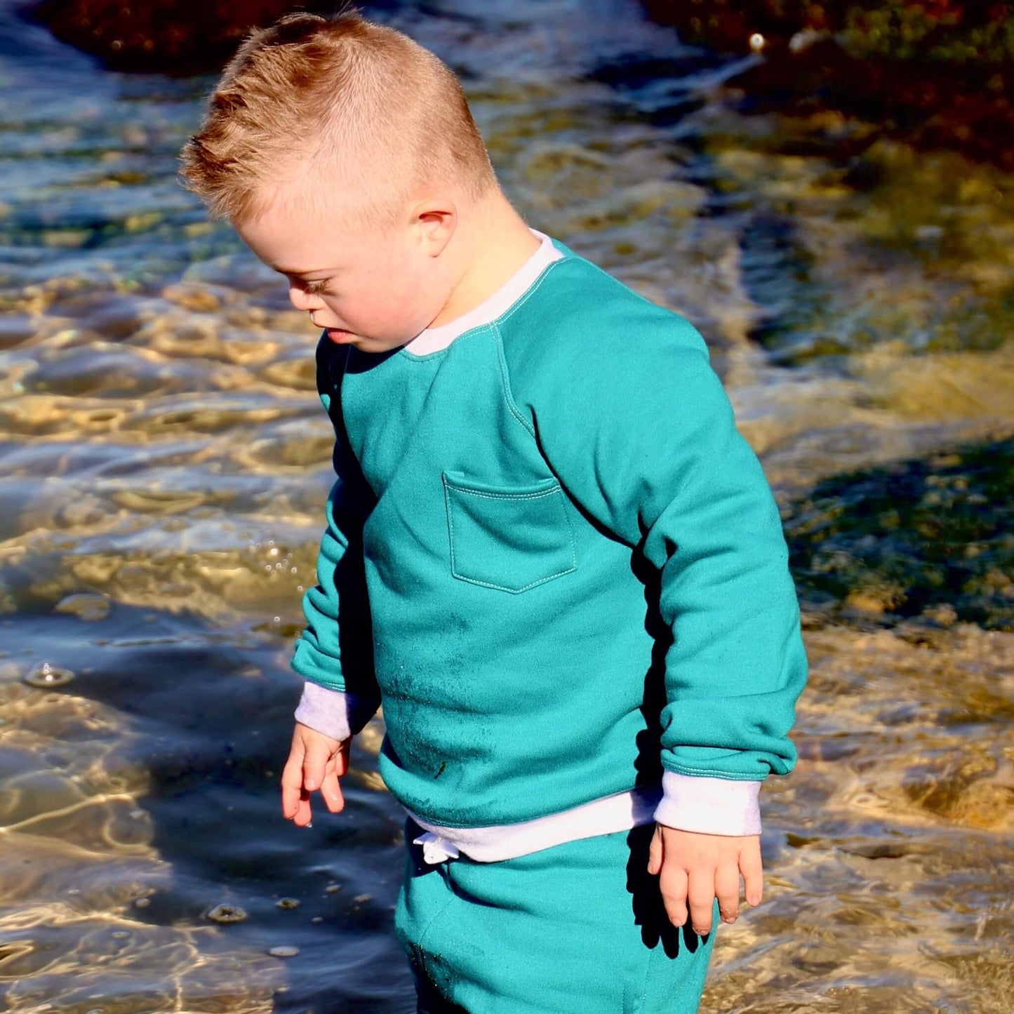 Boy wearing Jade coloured Winter Sweater featuring White Marle contrast rib at neck, hem and cuff with front pocket ethically made in Australia with Cotton blend cosy and warm Fleece