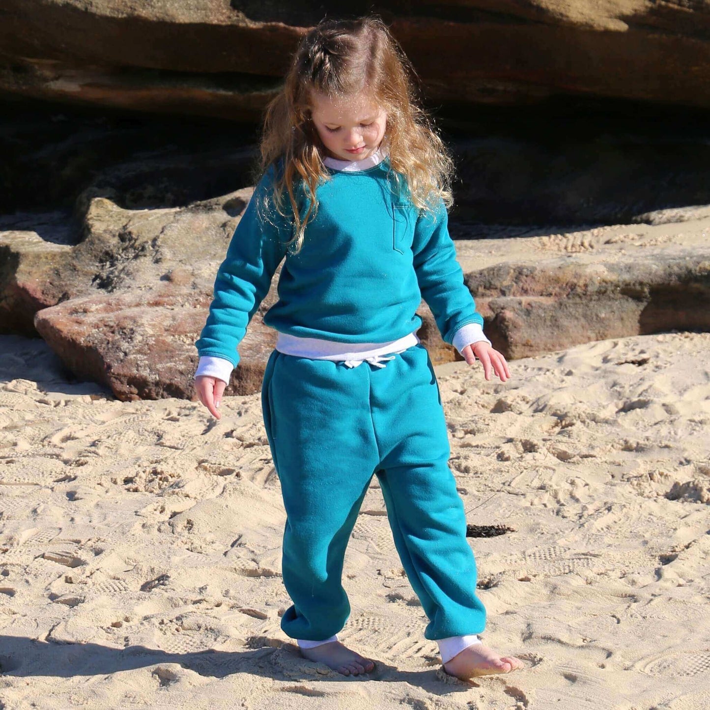 Girl wearing Jade colour trackpant featuring White contrast waistband, hem cuffs and drawcord, side pockets. Ethically made in Australia with cotton blend cosy and warm fleece