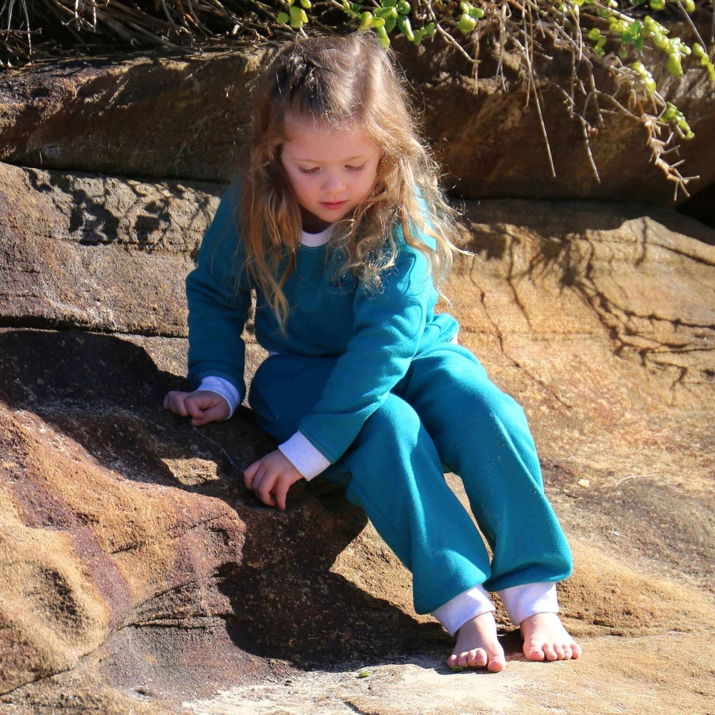 Girl wearing Jade colour trackpant featuring White contrast waistband, hem cuffs and drawcord, side pockets. Ethically made in Australia with cotton blend cosy and warm fleece