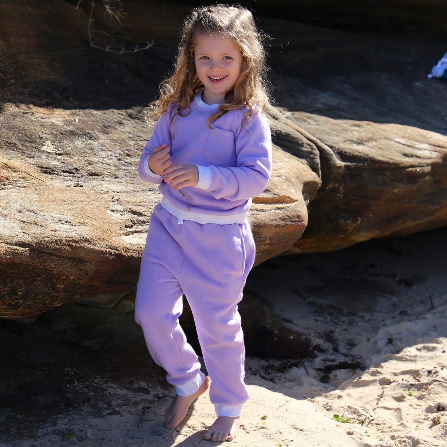 Girl wearing Lilac colour trackpant featuring White contrast waistband, hem cuffs and drawcord, side pockets. Ethically made in Australia with cotton blend cosy and warm fleece