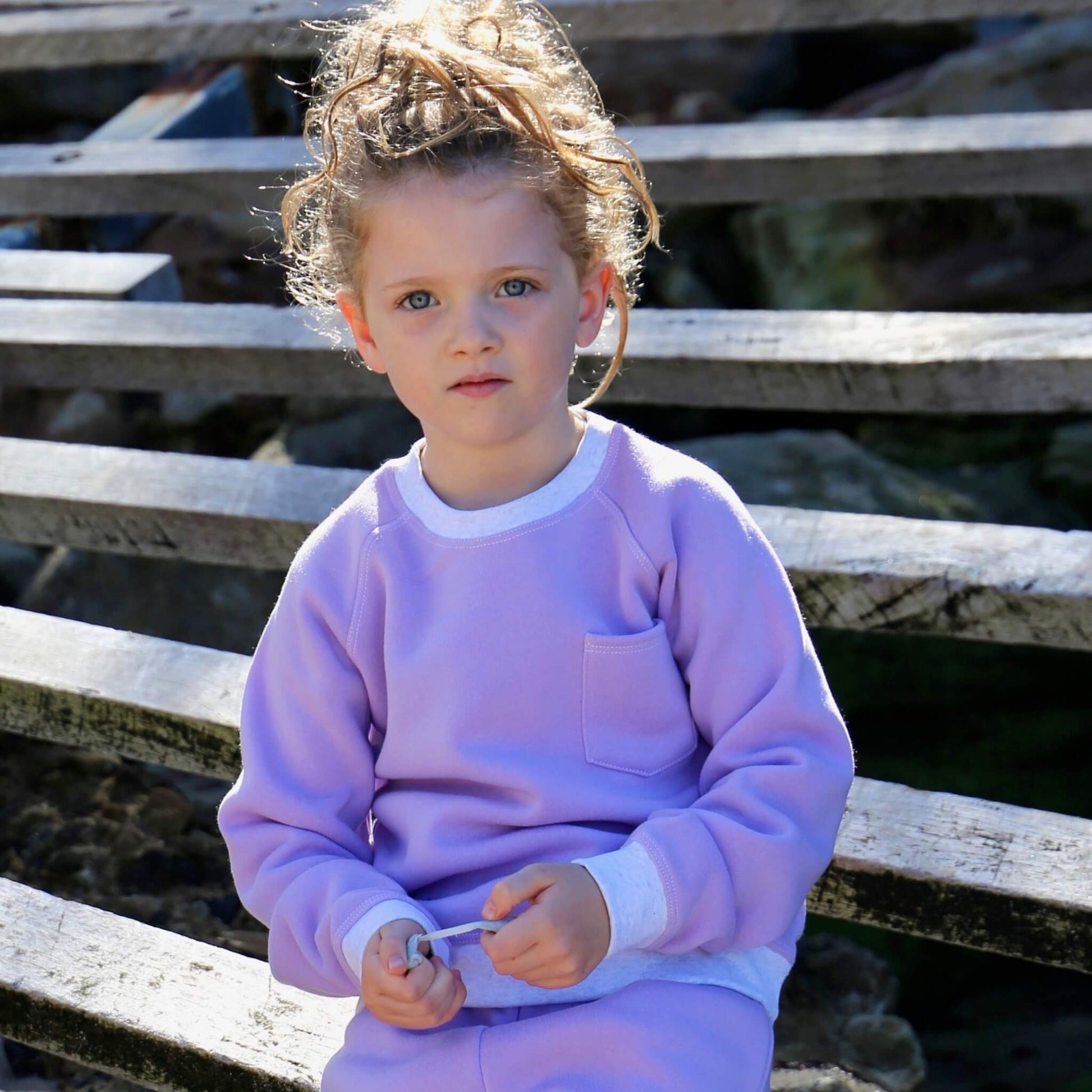 Girl wearing Lilac coloured Winter Sweater featuring White Marle contrast rib at neck, hem and cuff with front pocket ethically made in Australia with Cotton blend cosy and warm Fleece