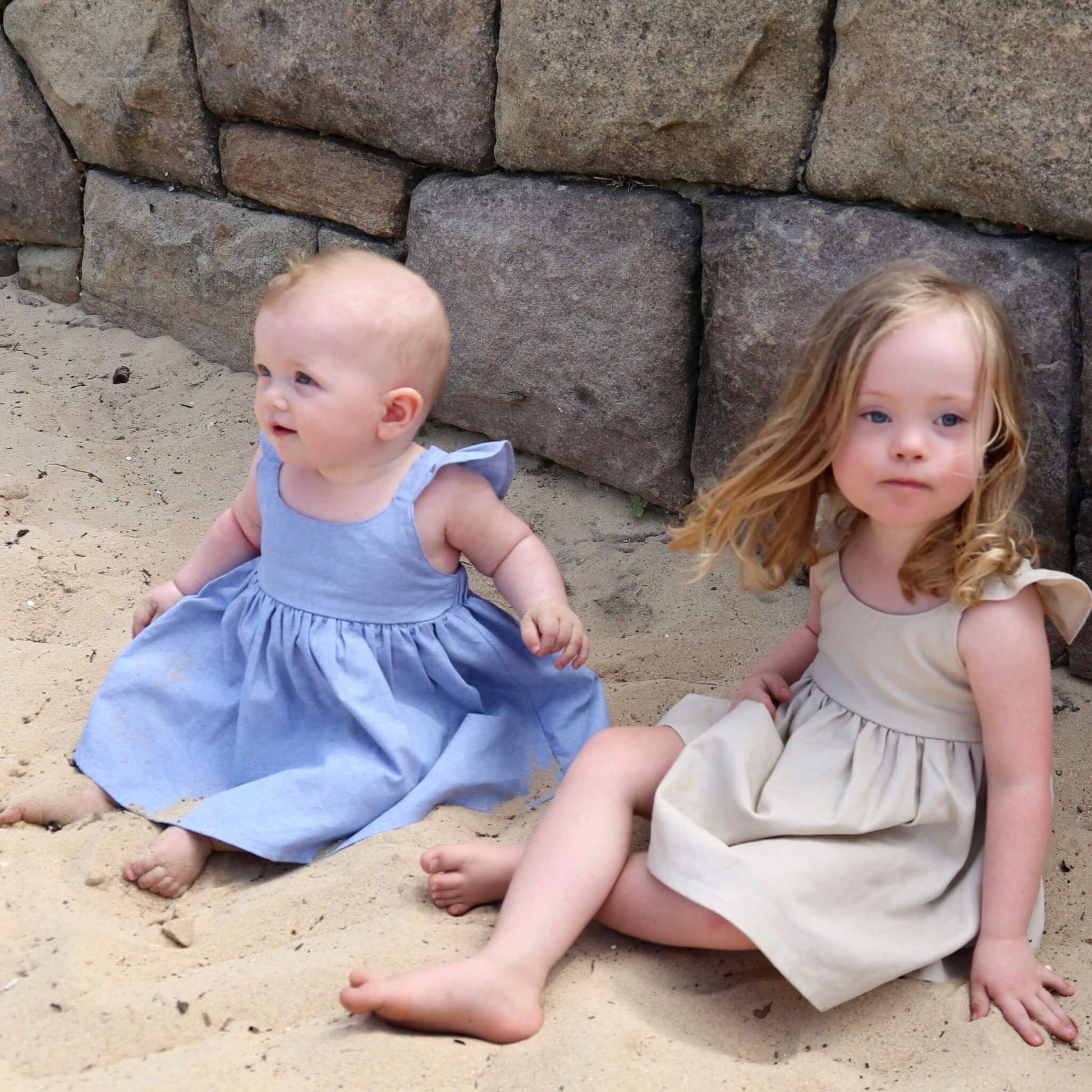 Girl wearing Linen colour Dress featuring a gathered skirt and frill on back crossed straps. Ethically made in Australia with a Linen Cotton blend fabric