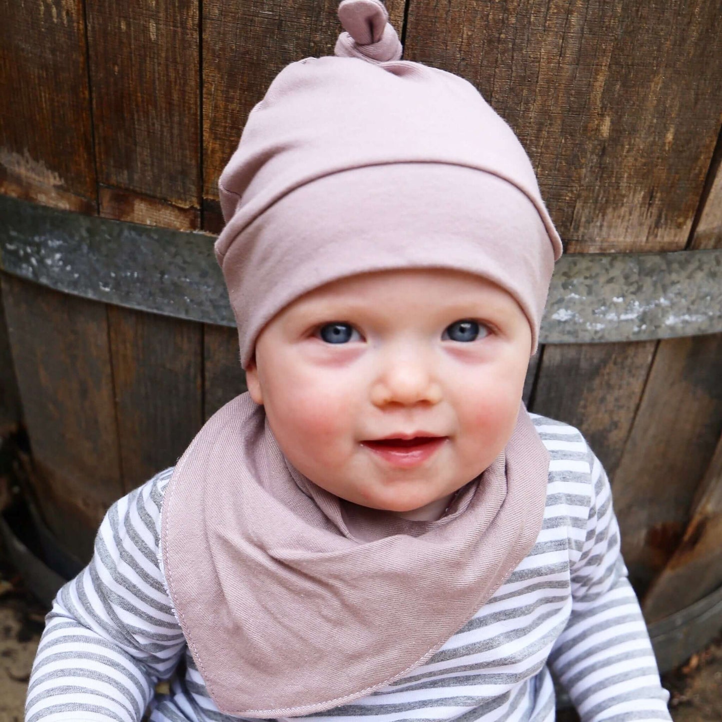 baby wearing musk colour dribble bib. ethically made in australia with 100% cotton jersey and terry towelling lining.