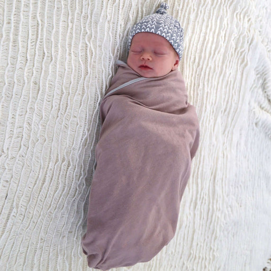 baby girl wrapped in muskl colour swaddle. Ethically made in australia with 100% cotton jersey