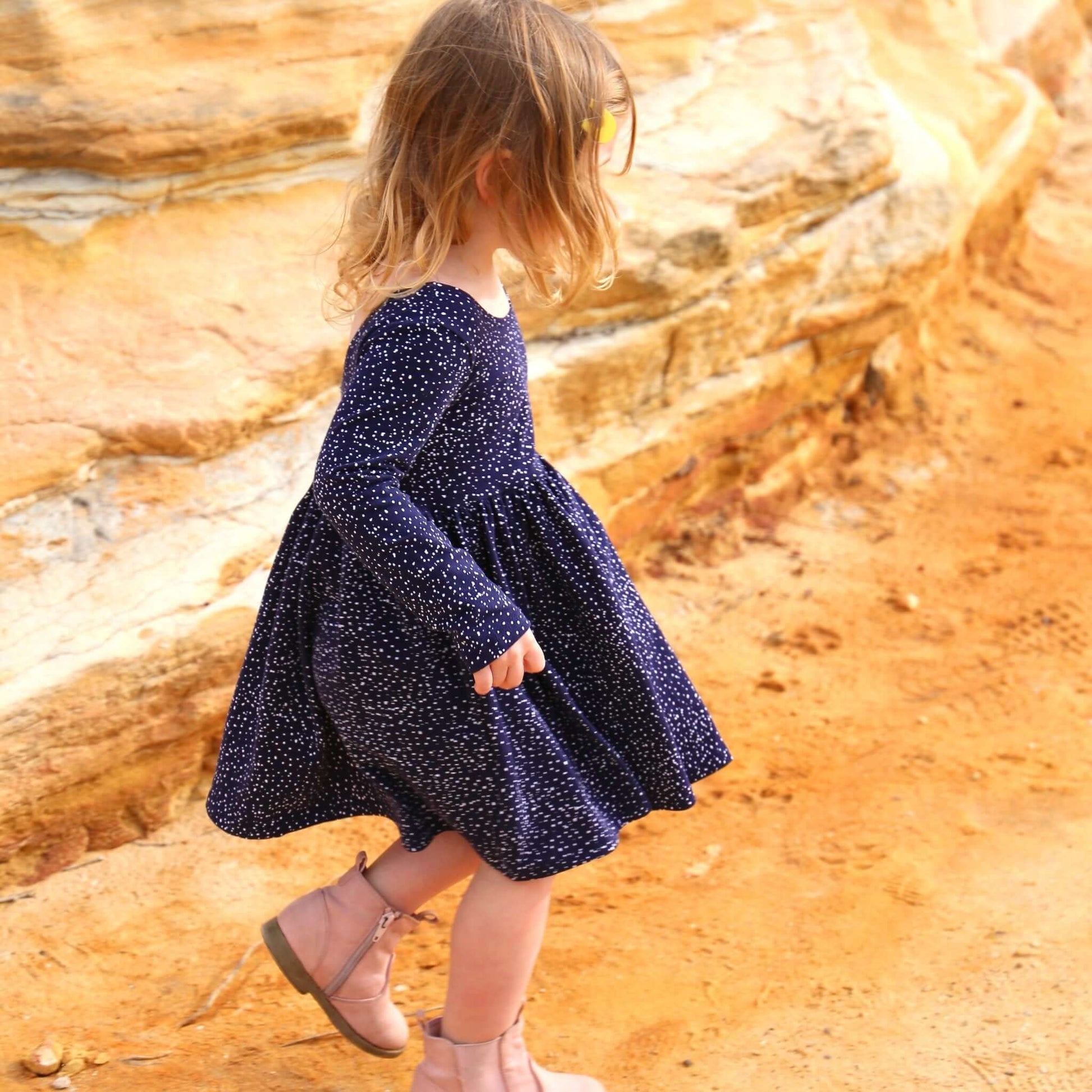 girl wearing navy printed dress featuring low back and gathered waist skirt.  Ethically made in australia with a stretch cotton jersey fabric.