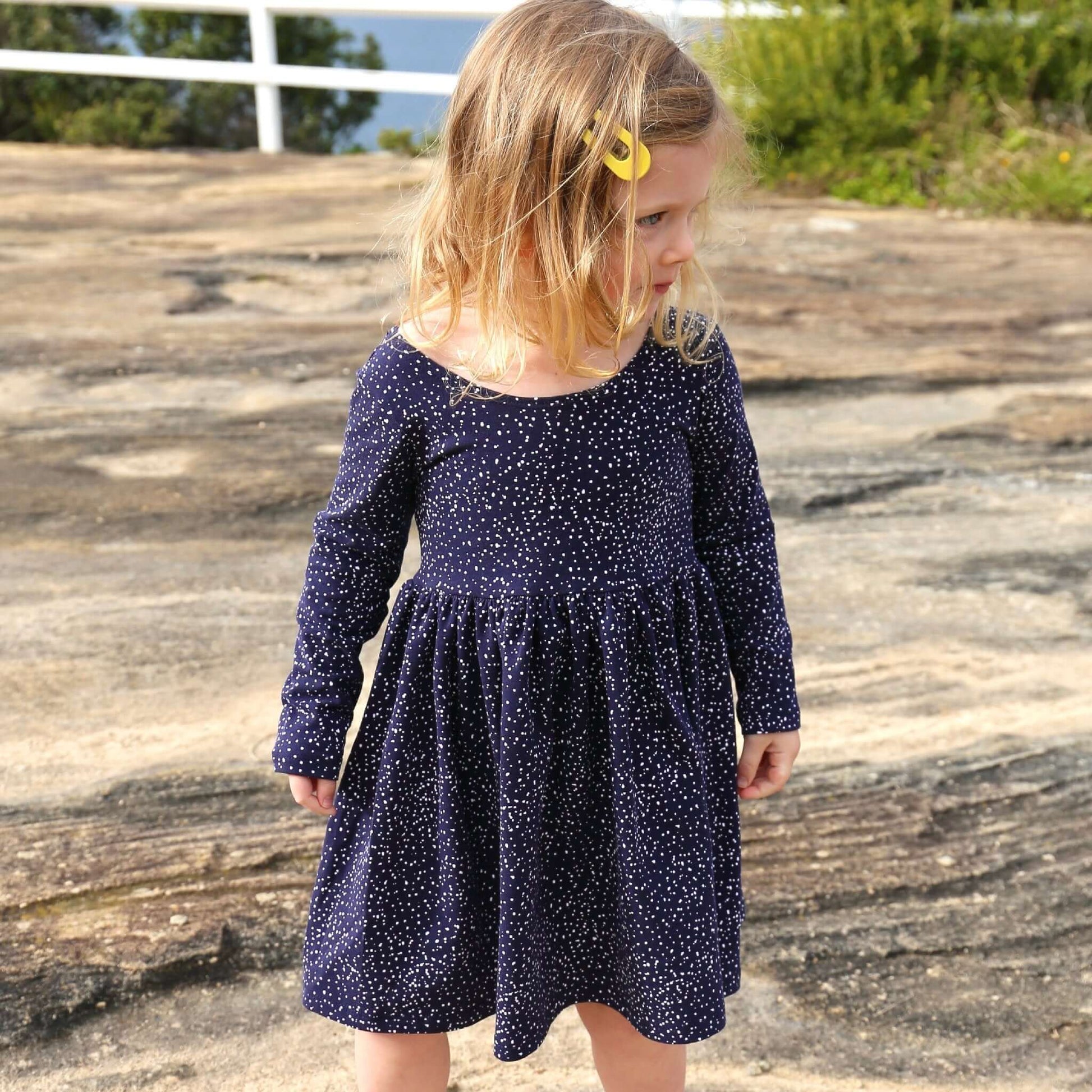 girl wearing navy printed dress featuring low back and gathered waist skirt.  Ethically made in australia with a stretch cotton jersey fabric.