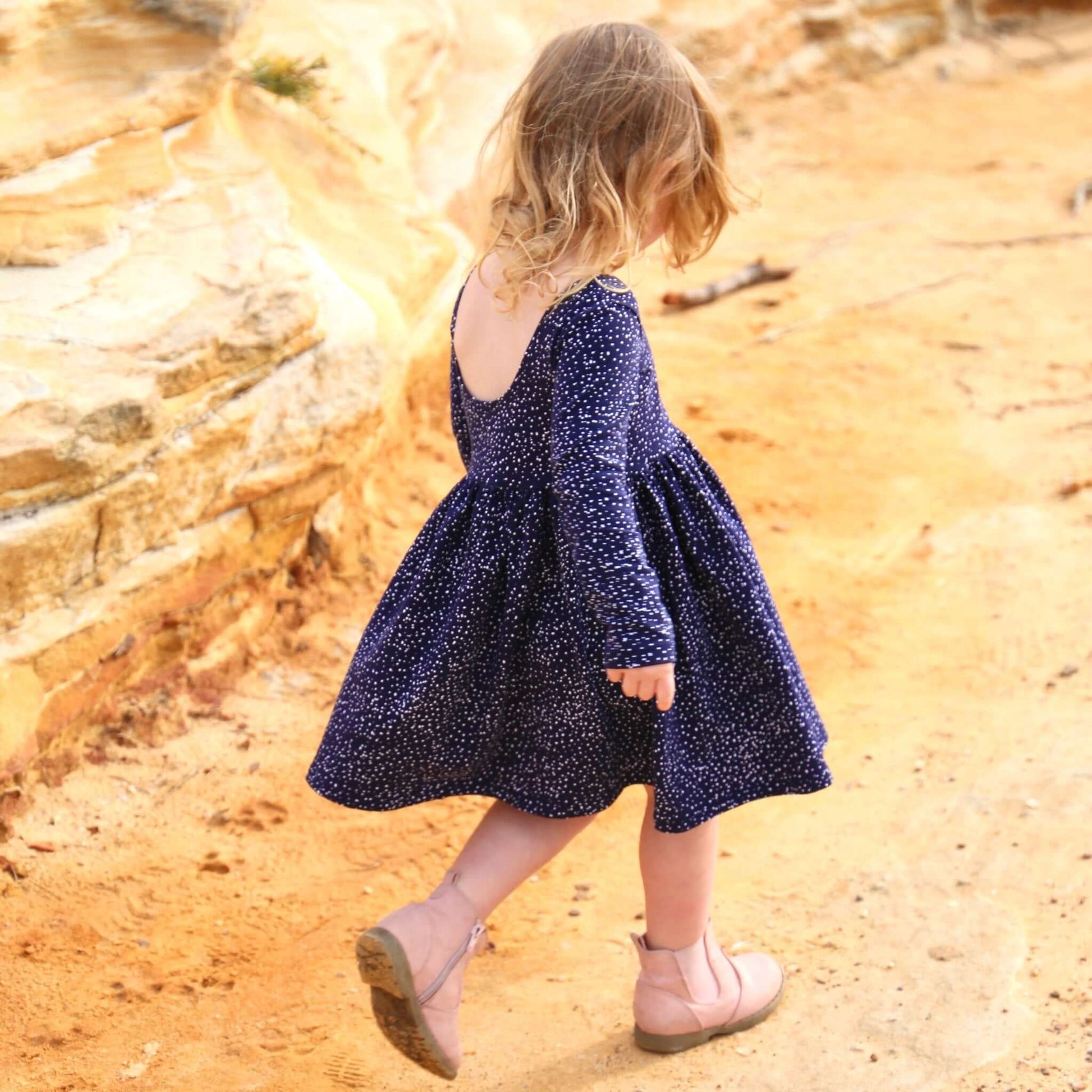 girl wearing navy printed dress featuring low back and gathered waist skirt.  Ethically made in australia with a stretch cotton jersey fabric.