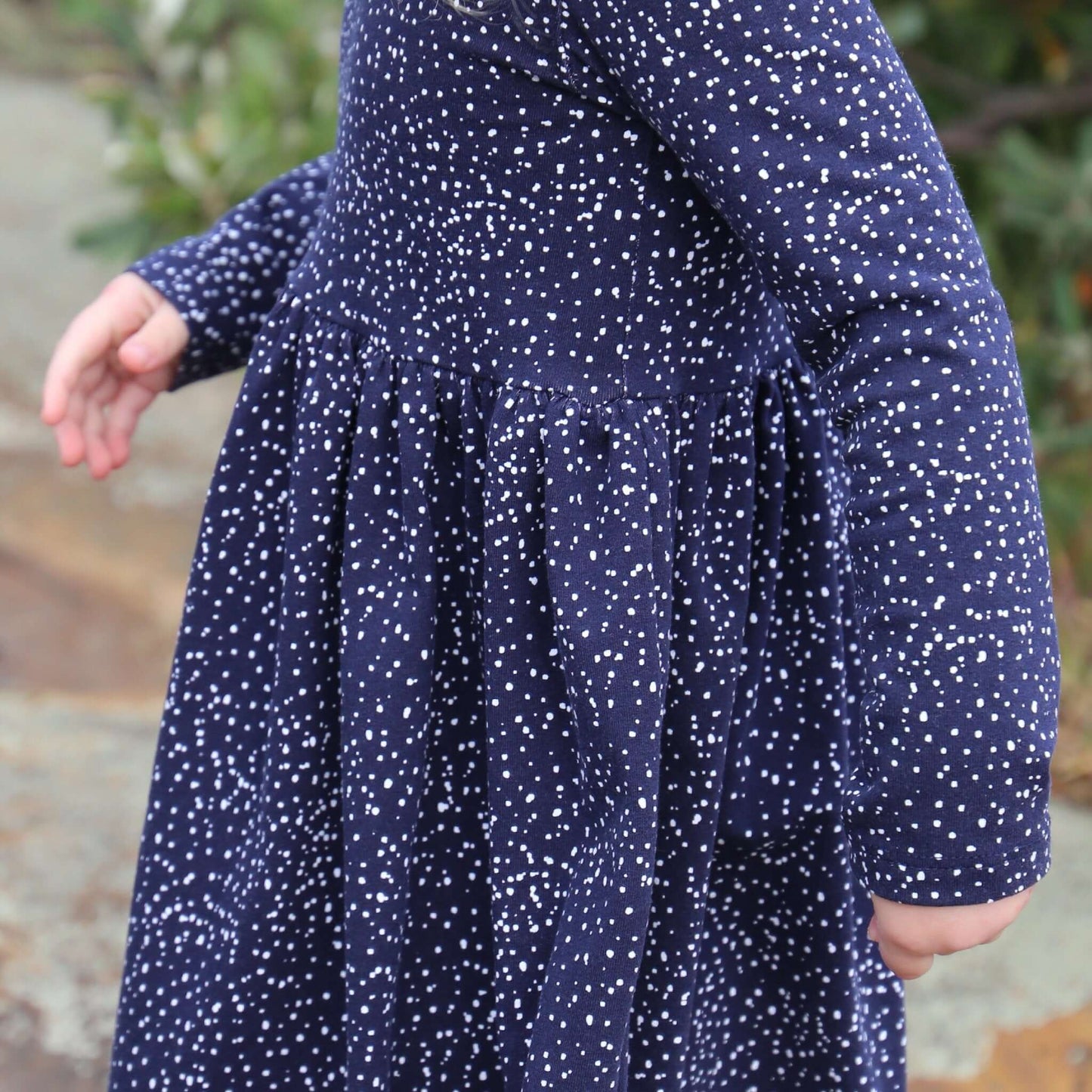 girl wearing navy printed dress featuring low back and gathered waist skirt.  Ethically made in australia with a stretch cotton jersey fabric.