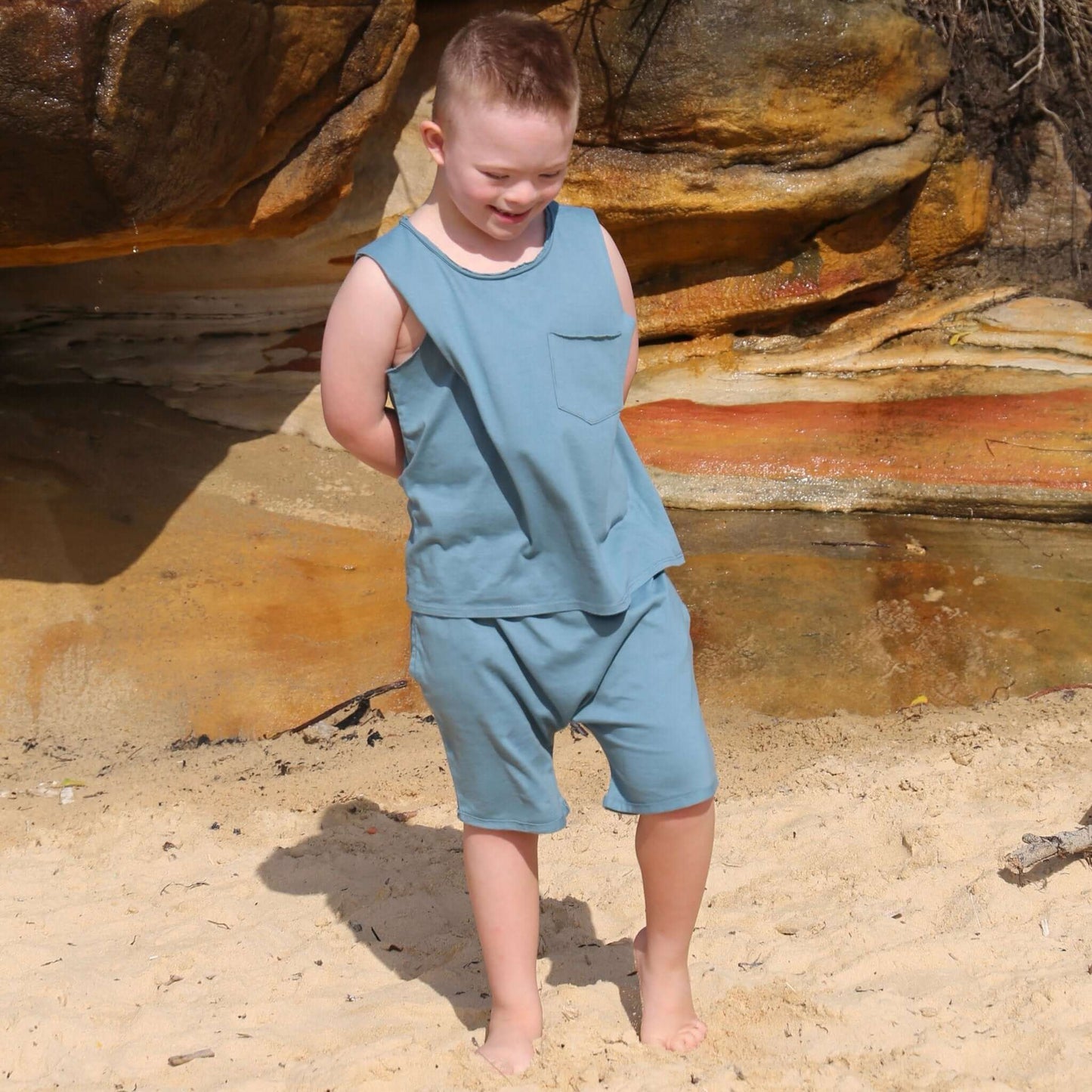 Boy wearing Ocean colour drop crotch shorts with contrast white drawcord and elastic waistband.  ethically made in australia with 100% cotton jersey.