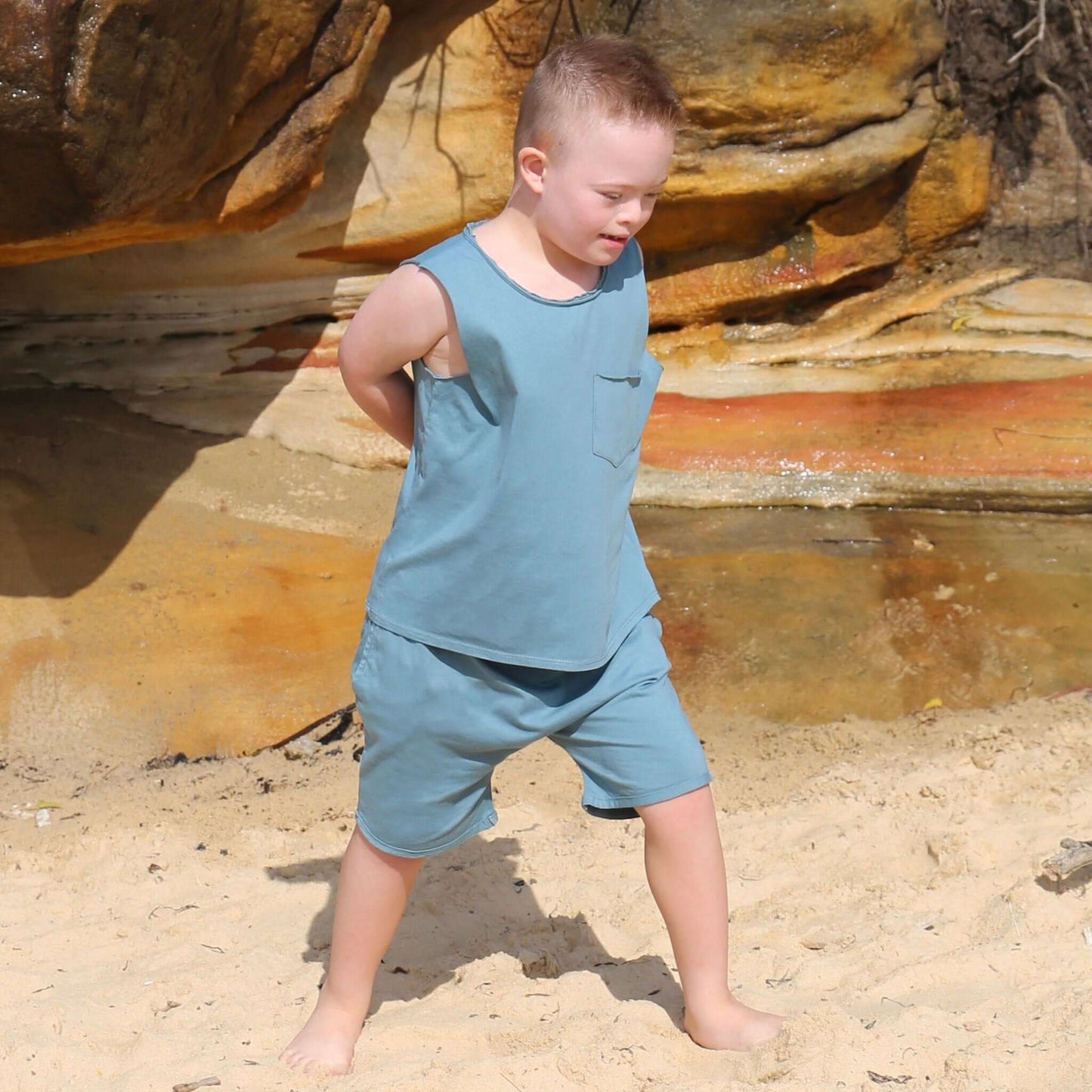 boy wearing ocean colour singlet with front pocket, raw edge armhole and neckline. Ethically made in australia with 100% cotton jersey