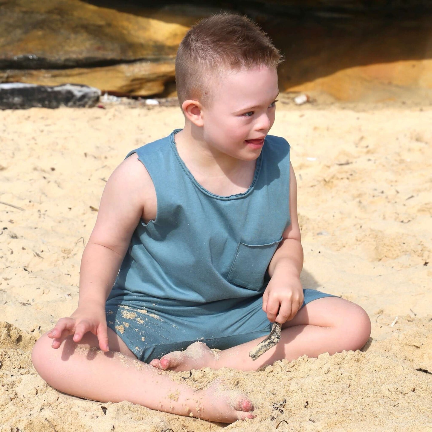 boy wearing ocean colour singlet with front pocket, raw edge armhole and neckline. Ethically made in australia with 100% cotton jersey