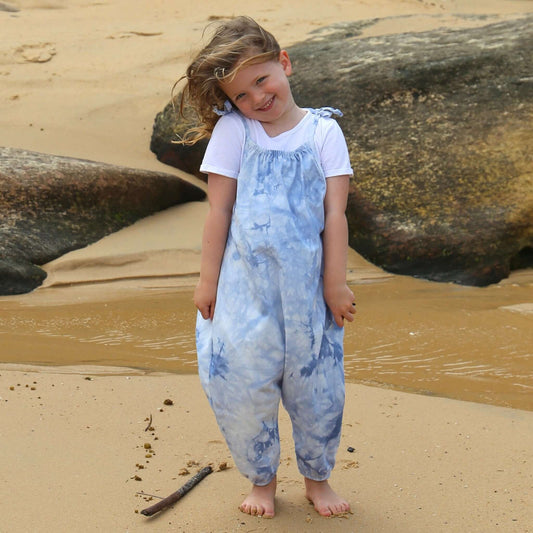 girl wearing light blue tie dye romper featuring tie straps and elastic leg cuff. ethically made in australia with stretch cotton drill