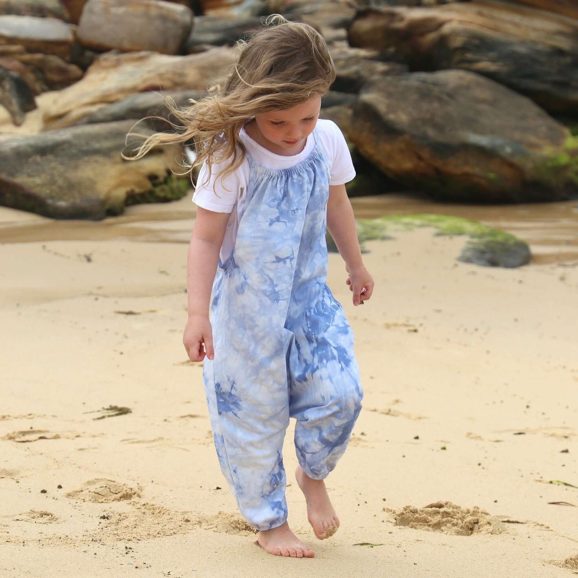 girl wearing light blue tie dye romper featuring tie straps and elastic leg cuff. ethically made in australia with stretch cotton drill