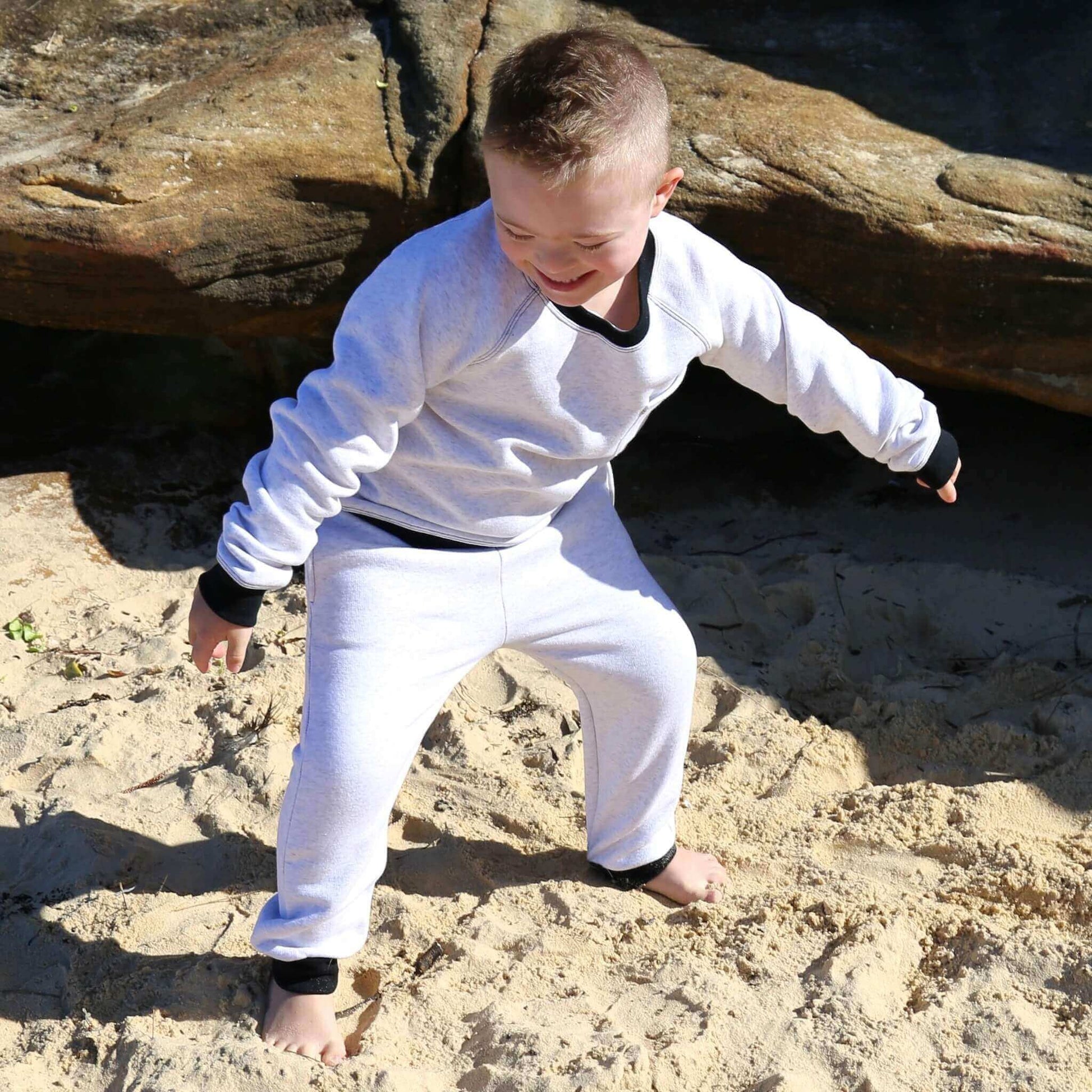 Boy wearing White Marle trackpant featuring black contrast waistband, hem cuffs and drawcord, side pockets. Ethically made in Australia with cotton blend cosy and warm fleece