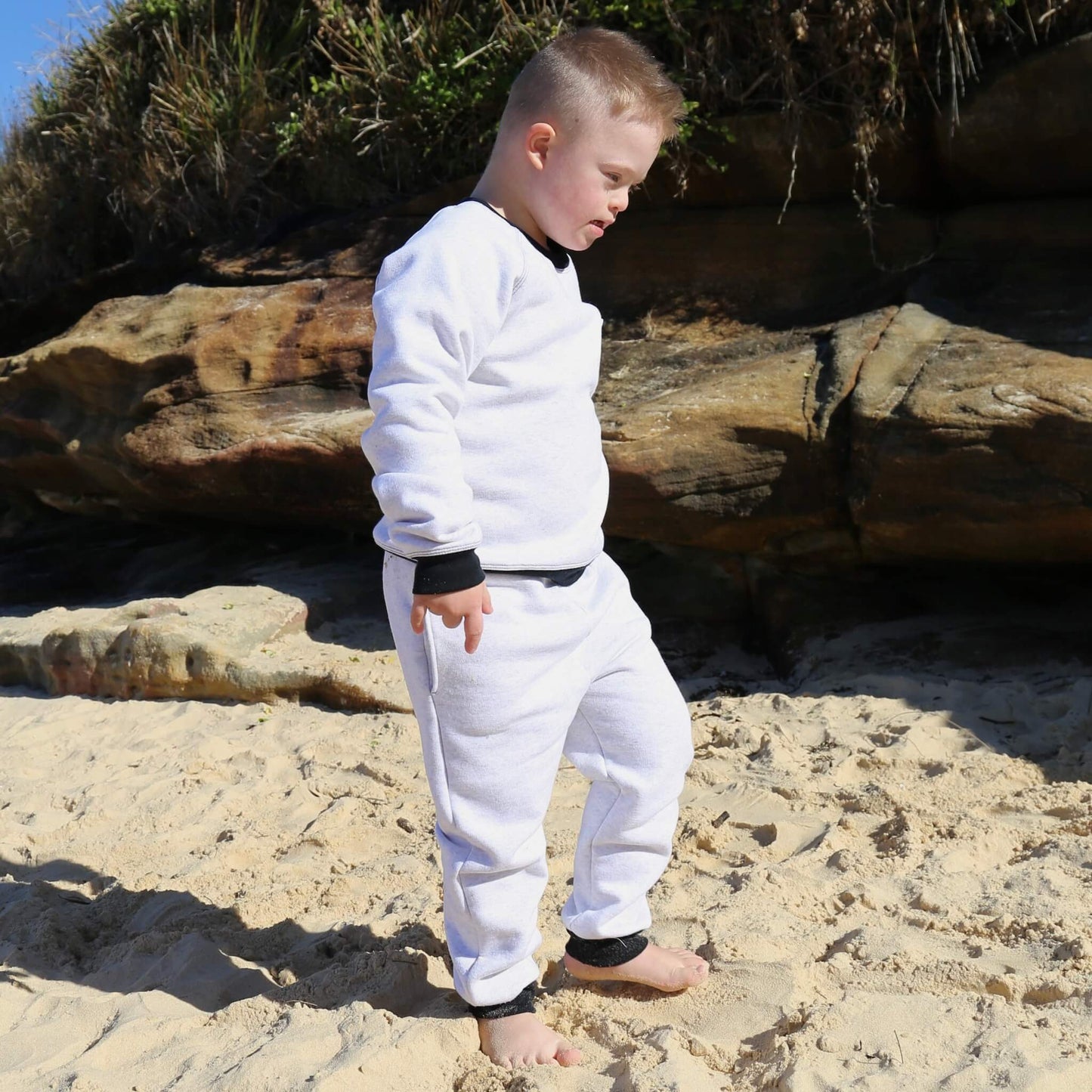 Boy wearing White Marle trackpant featuring black contrast waistband, hem cuffs and drawcord, side pockets. Ethically made in Australia with cotton blend cosy and warm fleece