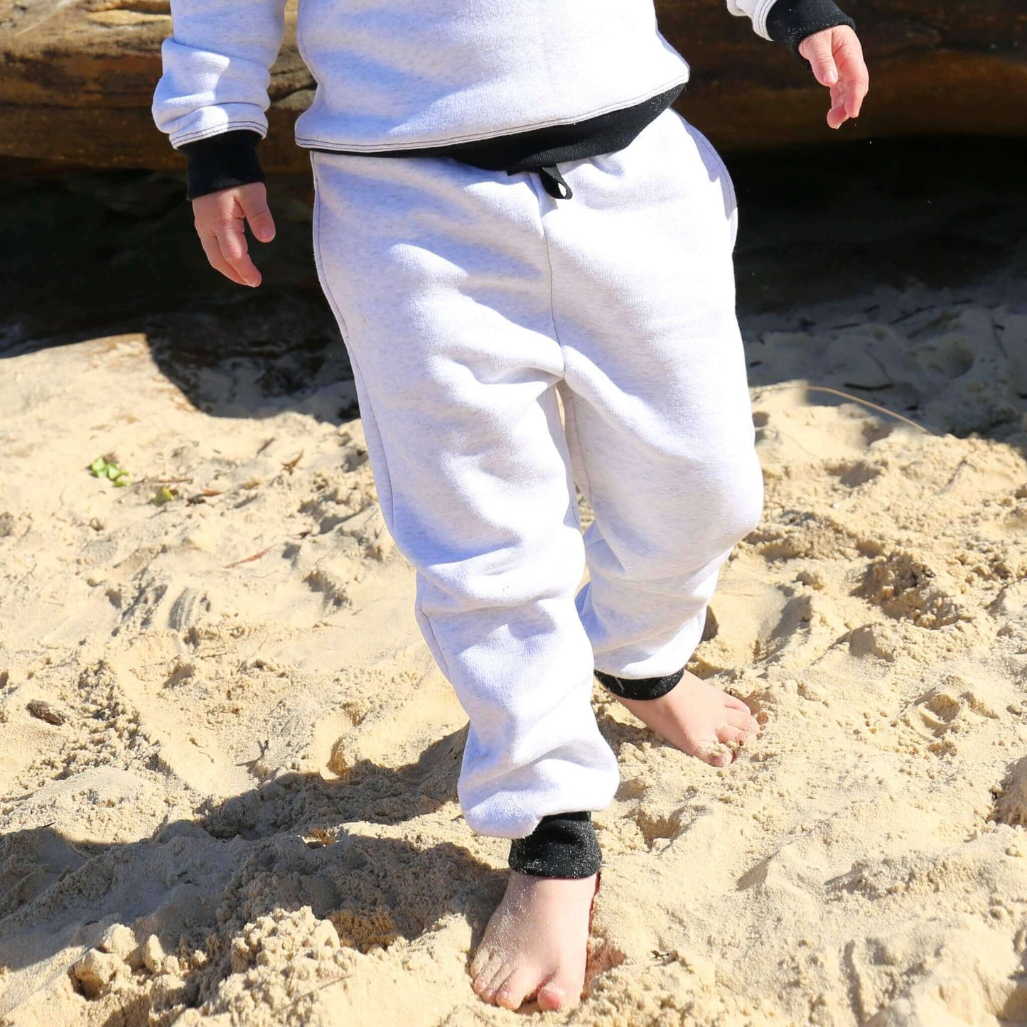 Boy wearing White Marle trackpant featuring black contrast waistband, hem cuffs and drawcord, side pockets. Ethically made in Australia with cotton blend cosy and warm fleece