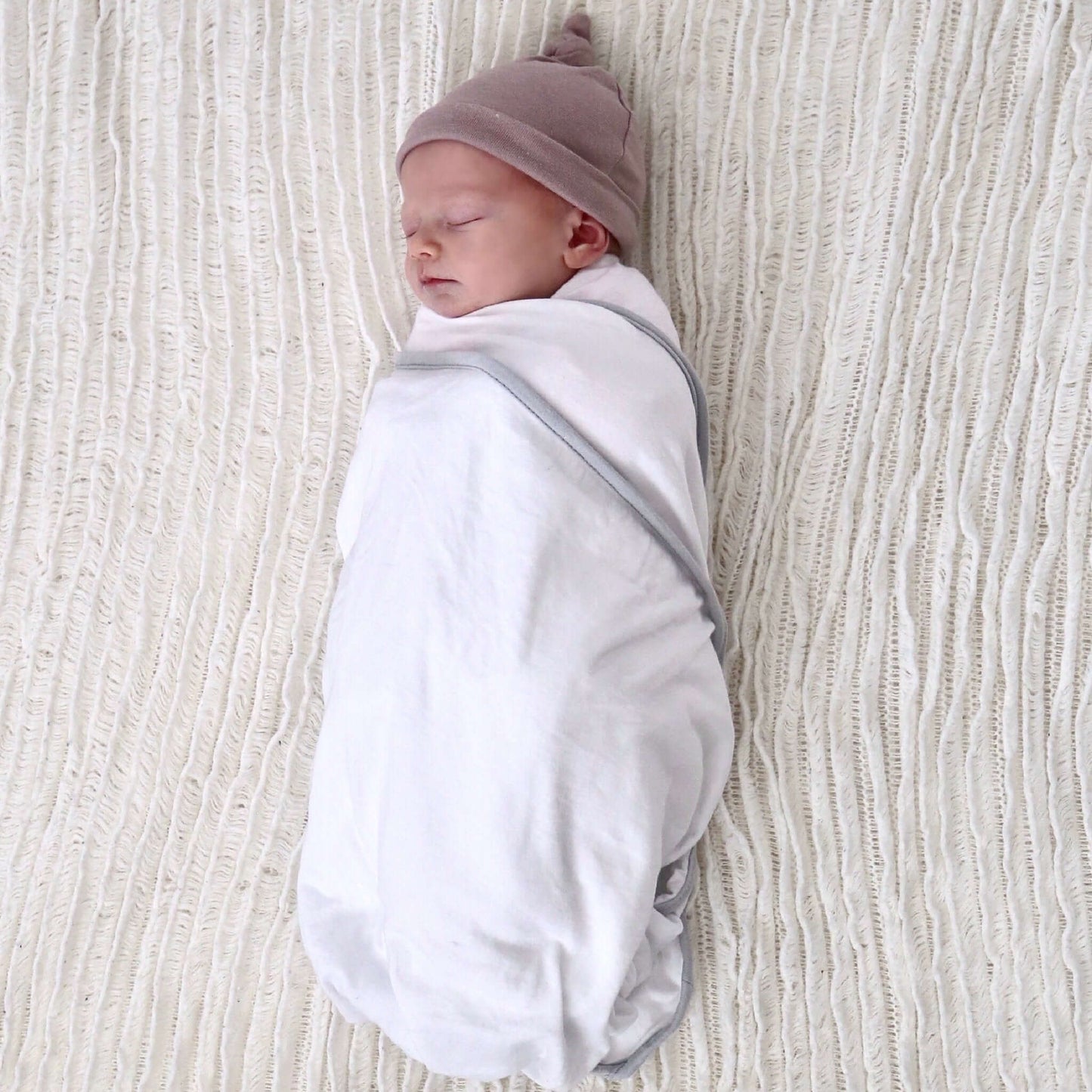 baby girl wrapped in white colour swaddle. Ethically made in australia with 100% cotton jersey