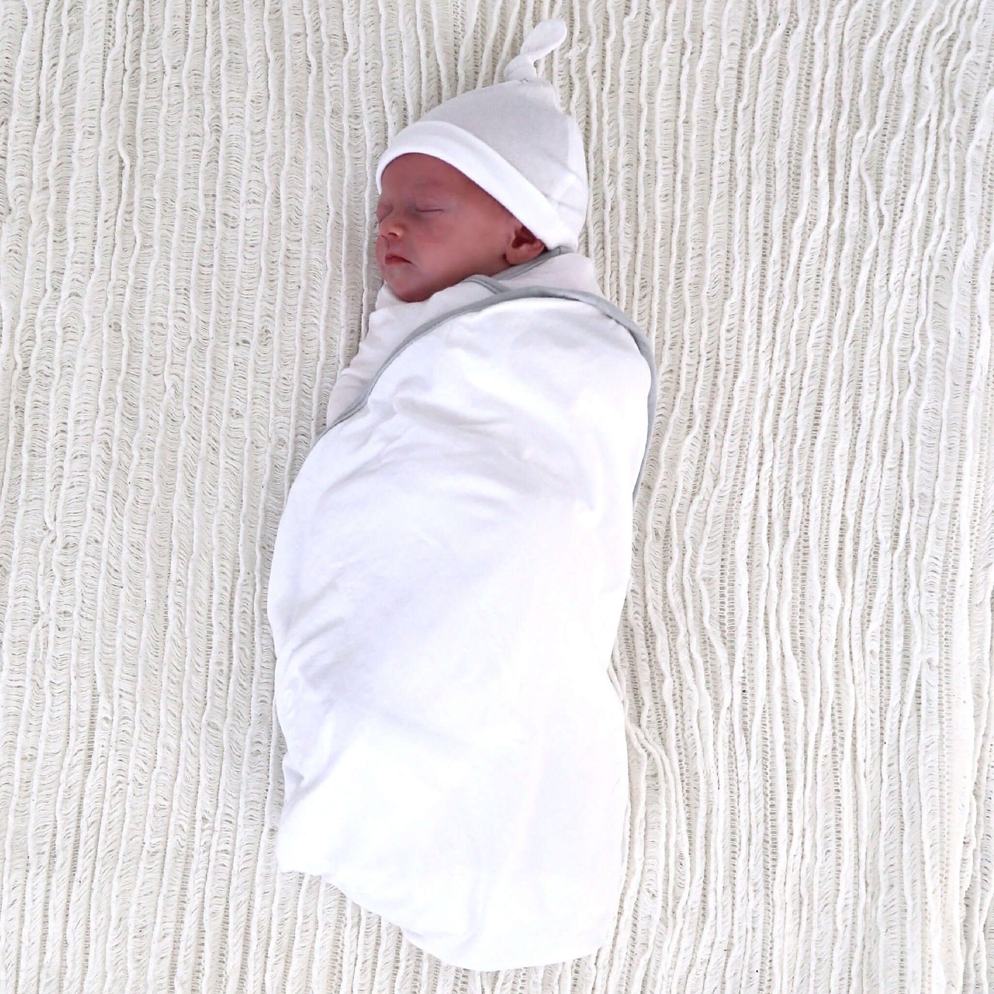 baby girl wrapped in white colour swaddle. Ethically made in australia with 100% cotton jersey