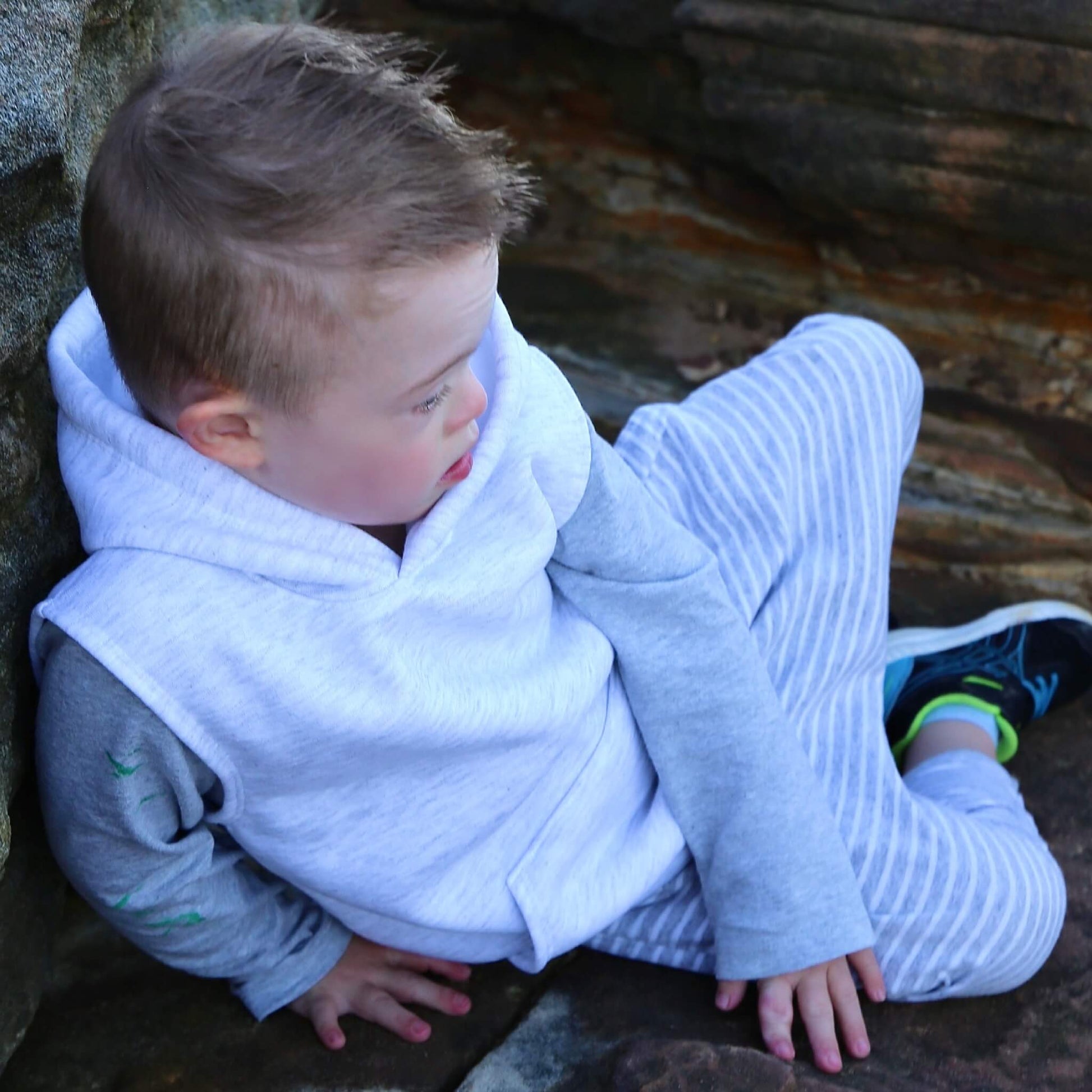 Boy wearing White Marle Sleeveless Hoodie ethically made in Australia with a Cotton blend soft cosy Fleece. Worn over Grey Marle long sleeve tshirt with stripe Harem Pants